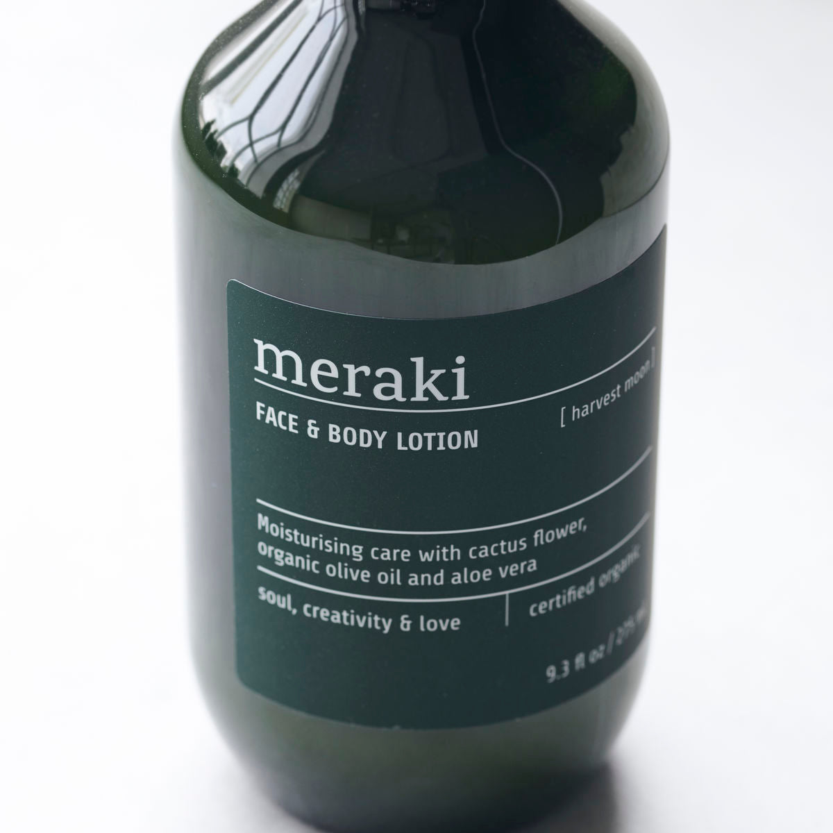 A green bottle of Meraki Face & Body Lotion Organic, Harvest Moon—an ECOCERT Cosmos certified face and body lotion with moisturizing cactus flower, organic olive oil, and aloe vera.