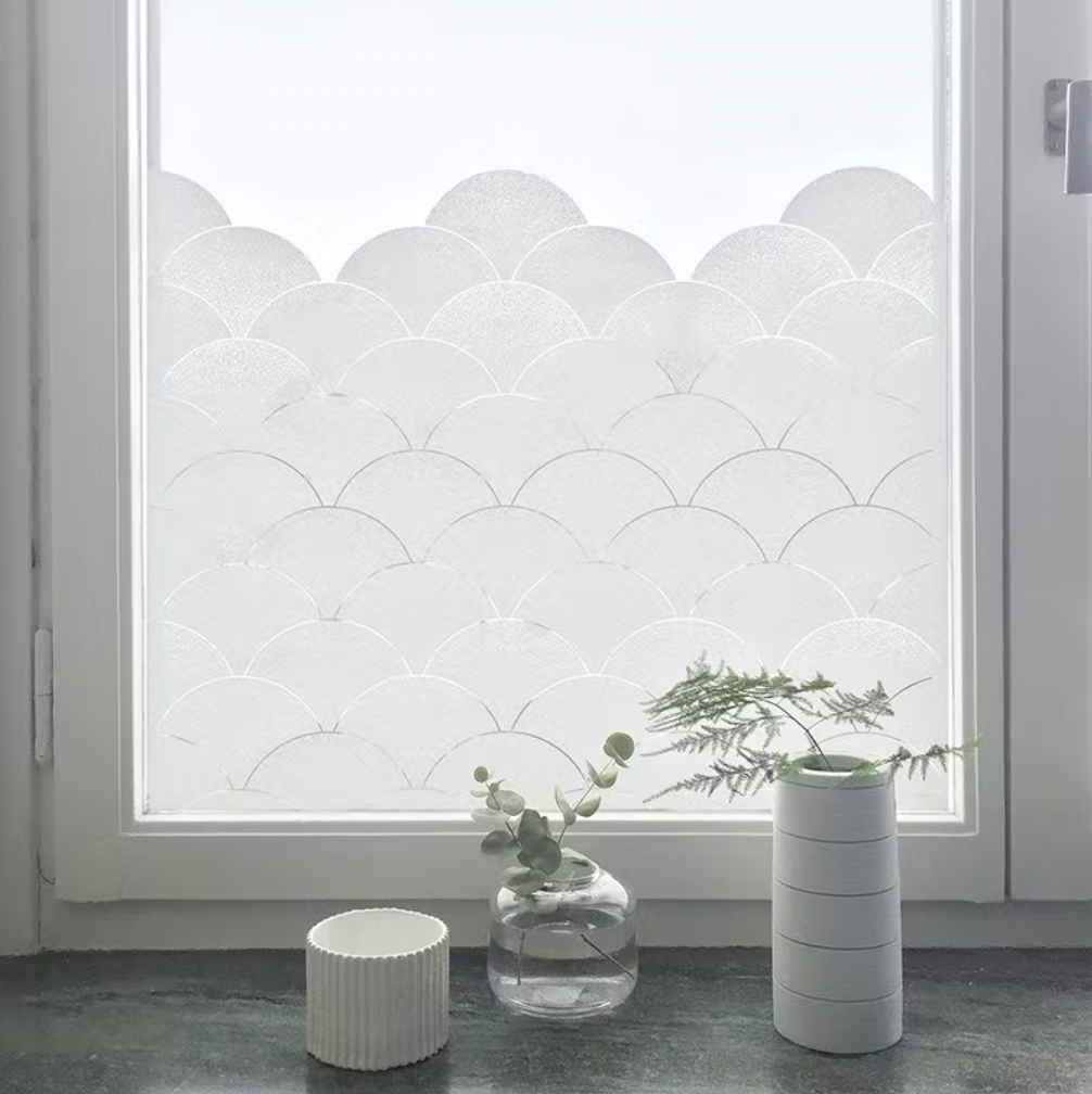 The BY MAY Stockholm Clouds Window Film (48 x 120cm) lets in soft light. On the sill, a ribbed cup, clear vase with greenery, and stacked white ring planter create a peaceful scene.