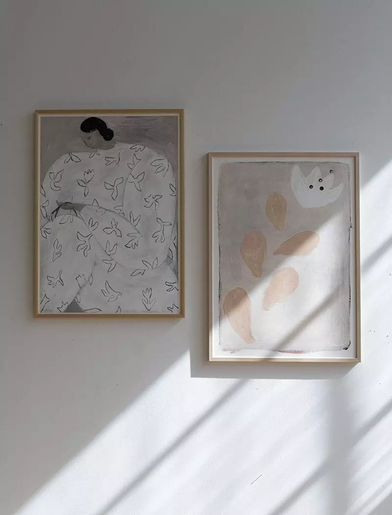 The Fine Little Day White Flower Print (50x70 cm) hangs on a light wall, its soft floral design illuminated as gentle shadows play across the surface.