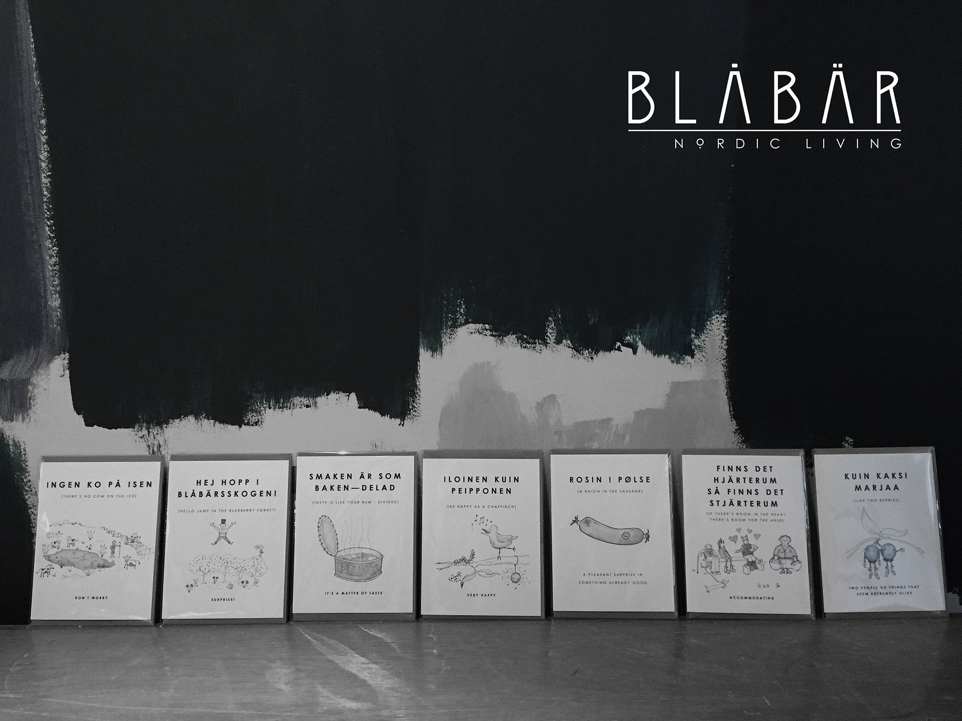 The Blåbär Nordic Living Greeting Card Smaken är som baken, delad stands out among quirky Swedish phrase cards displayed on wood, with the brand’s name featured in the top right corner to highlight this unique collection.