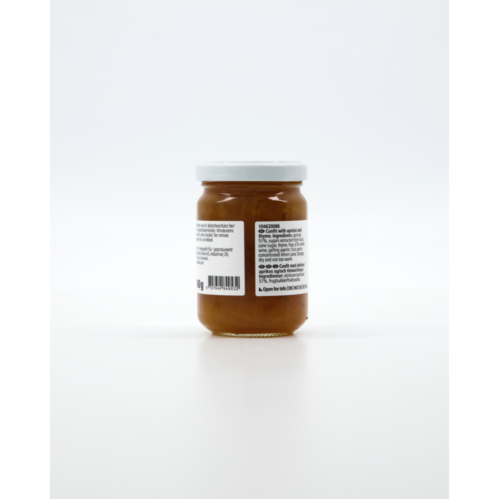 A small glass jar of Nicolas Vahé Confit, Apricot & Thyme with a white lid, filled with light brown confit. The back label and barcode are visible, photographed against a plain white background. Ideal for pairing with cheese.