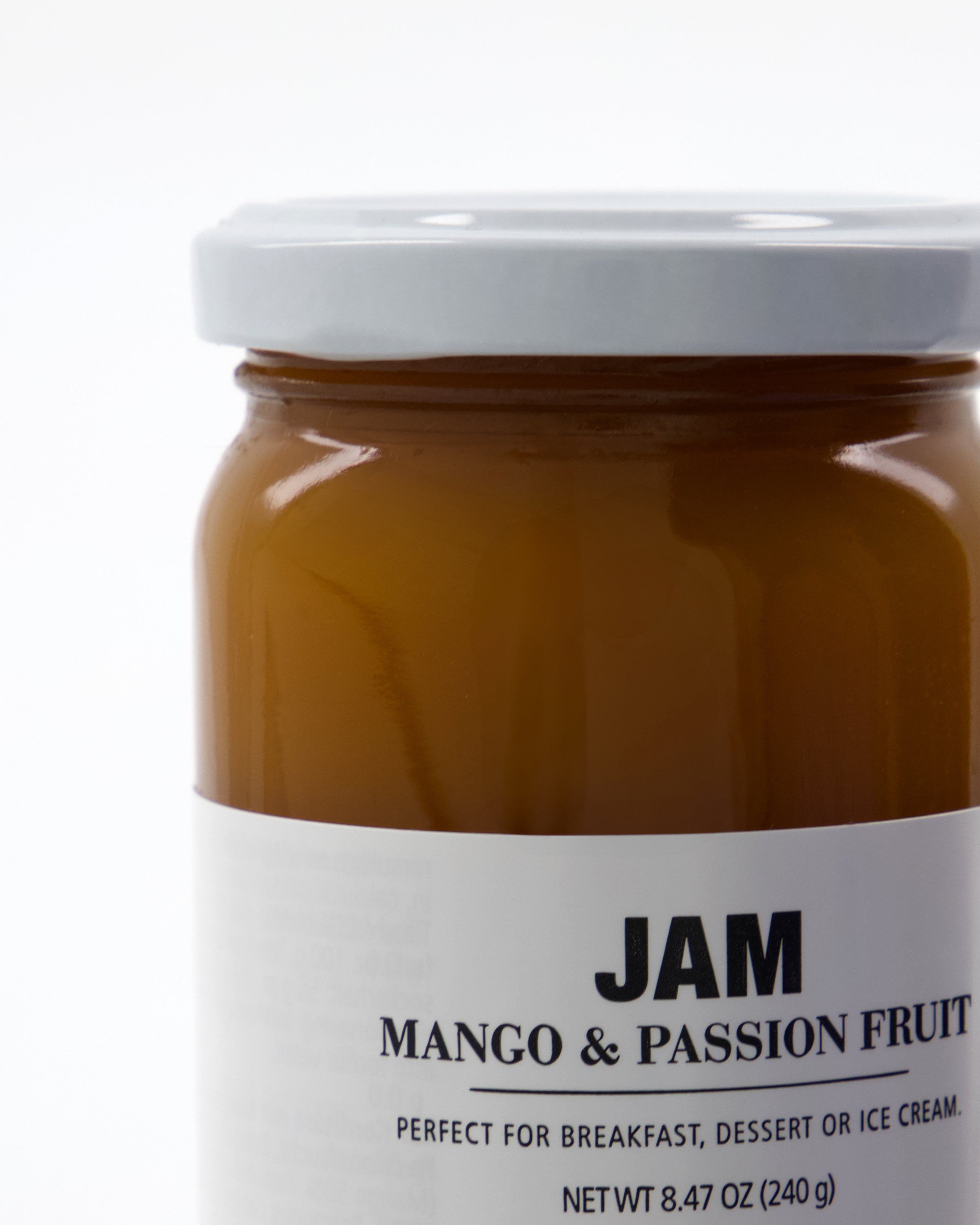A glass jar with a white lid and a label reading "Jam, Mango & Passion Fruit" from Nicolas Vahé. The jar contains vibrant orange jam that is delicious and versatile—perfect for breakfast, dessert, or as a topping for ice cream.