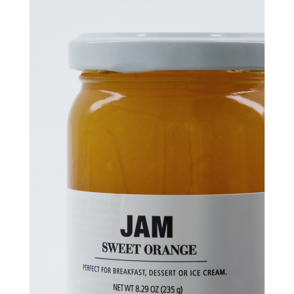 Close-up of a glass jar of Nicolas Vahé Jam Seasonal, Sweet Orange, featuring a white label that describes its citrus flavour and suitability for breakfast, dessert or ice cream.