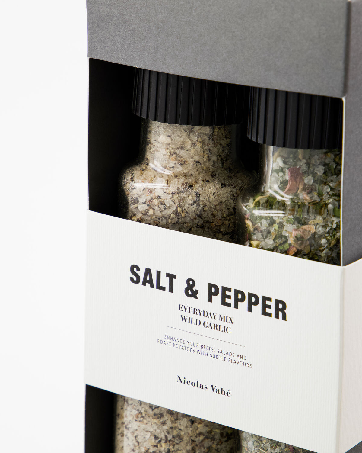 Close-up of the Gift Box, Everyday Mix Salt & Pepper and Wild Garlic Salt by Nicolas Vahé, featuring two spice grinders in a black and white package. The grinders contain seasoning blends with visible herbs, spices, and wild garlic salt.