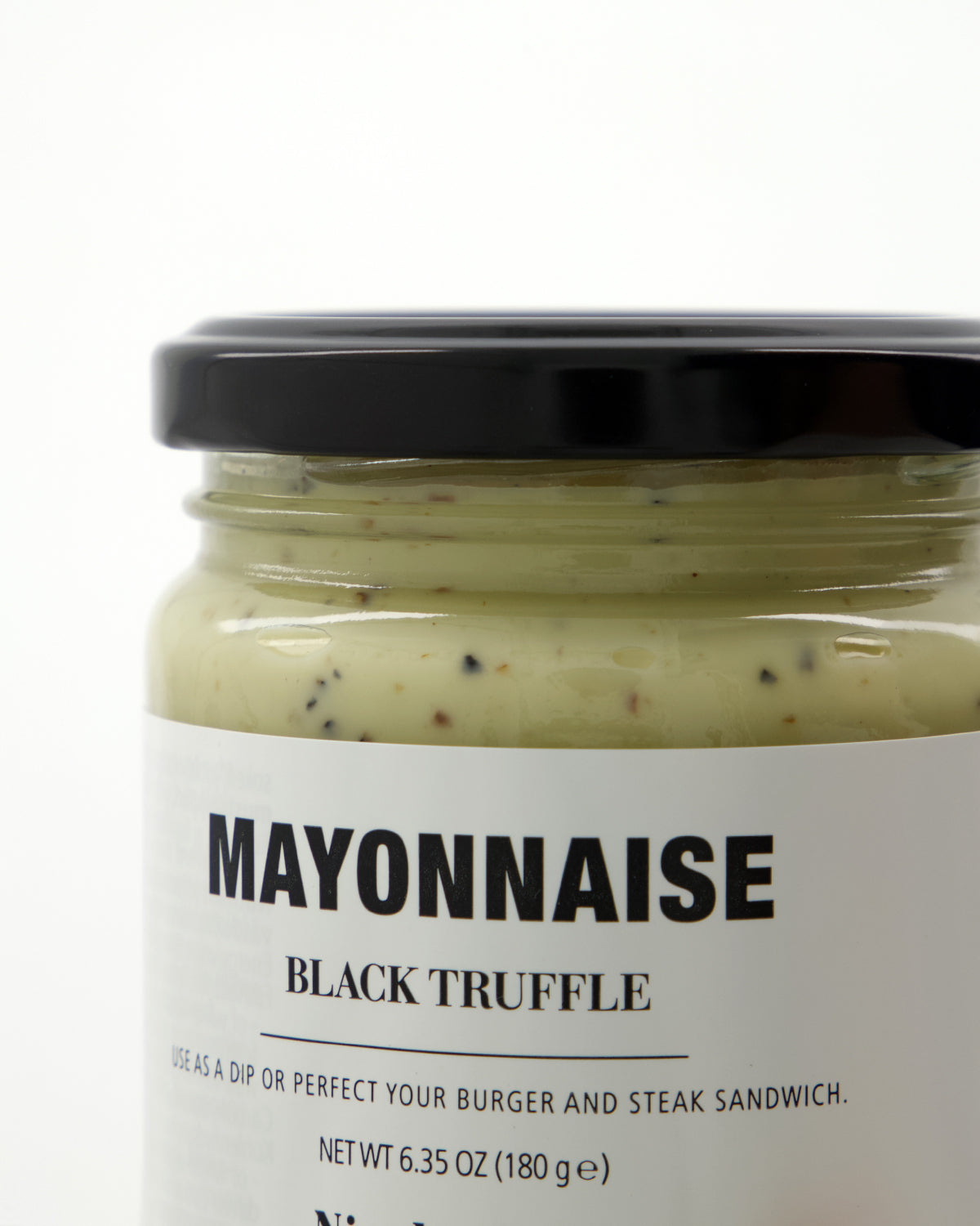 A close-up of a jar labeled “Mayonnaise, Black Truffle” by Nicolas Vahé. The jar contains creamy mayo infused with delicate black truffle specks and features a sleek black lid. This luxurious condiment from Nicolas Vahé adds gourmet flair to any dish.