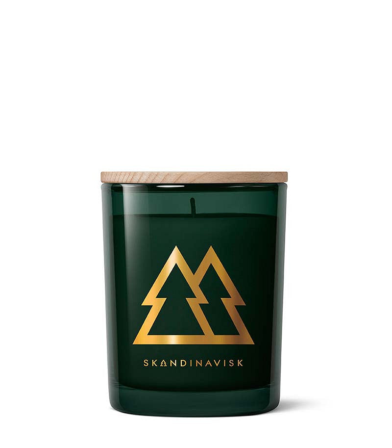 The Skandinavisk Seasonal Scented Candle Skog Gold Symbol (200 g) features a green glass jar with a wooden lid, adorned with two gold tree outlines and the brand name SKANDINAVISK in gold on the front. Crafted from Swedish rapeseed wax, this candle captures the fresh aroma of pine needles reminiscent of boreal forests.