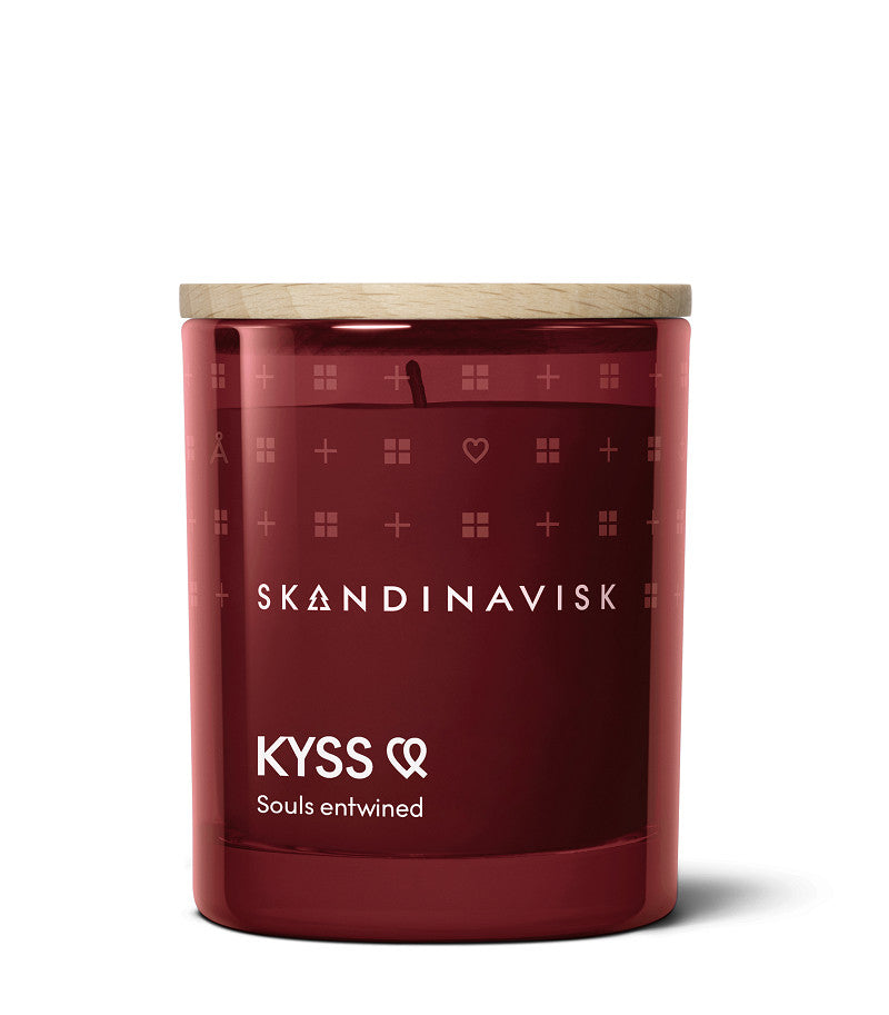 The Skandinavisk Scented Candle Kyss (65g) is a red Swedish rapeseed wax candle with an engraved beechwood lid, "KYSS Souls entwined" in white text, and minimalist branding on the glass container.