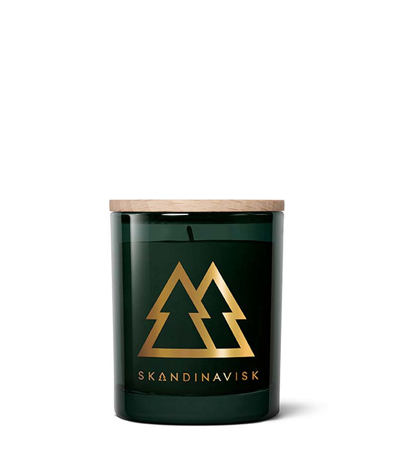 The Skandinavisk Seasonal Scented Candle Skog Gold Symbol (65 g) comes in a dark green jar with a wooden lid, adorned with a gold graphic of two pine trees and the word “SKANDINAVISK” below. Crafted from Swedish rapeseed wax, this candle captures the fresh pine needle aroma of Nordic woodlands.