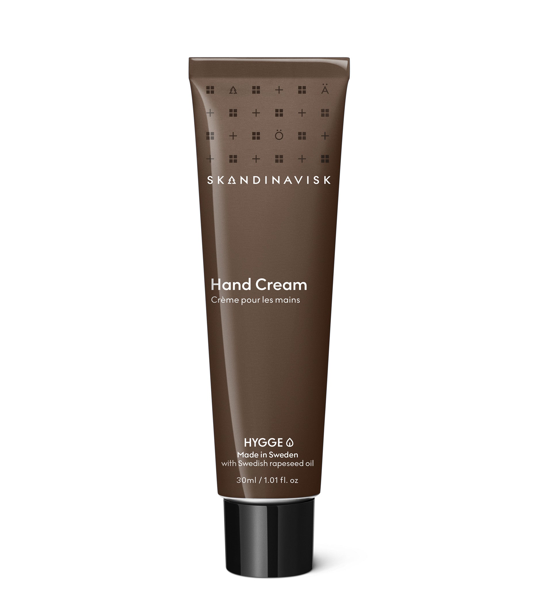 A 30 ml tube of Skandinavisk Mini Hand Cream Hygge in brown, displays white text with ingredients and size details. This Scandinavian skincare essential contains organic aloe vera for gentle hydration, and is shown standing upright on a white background.