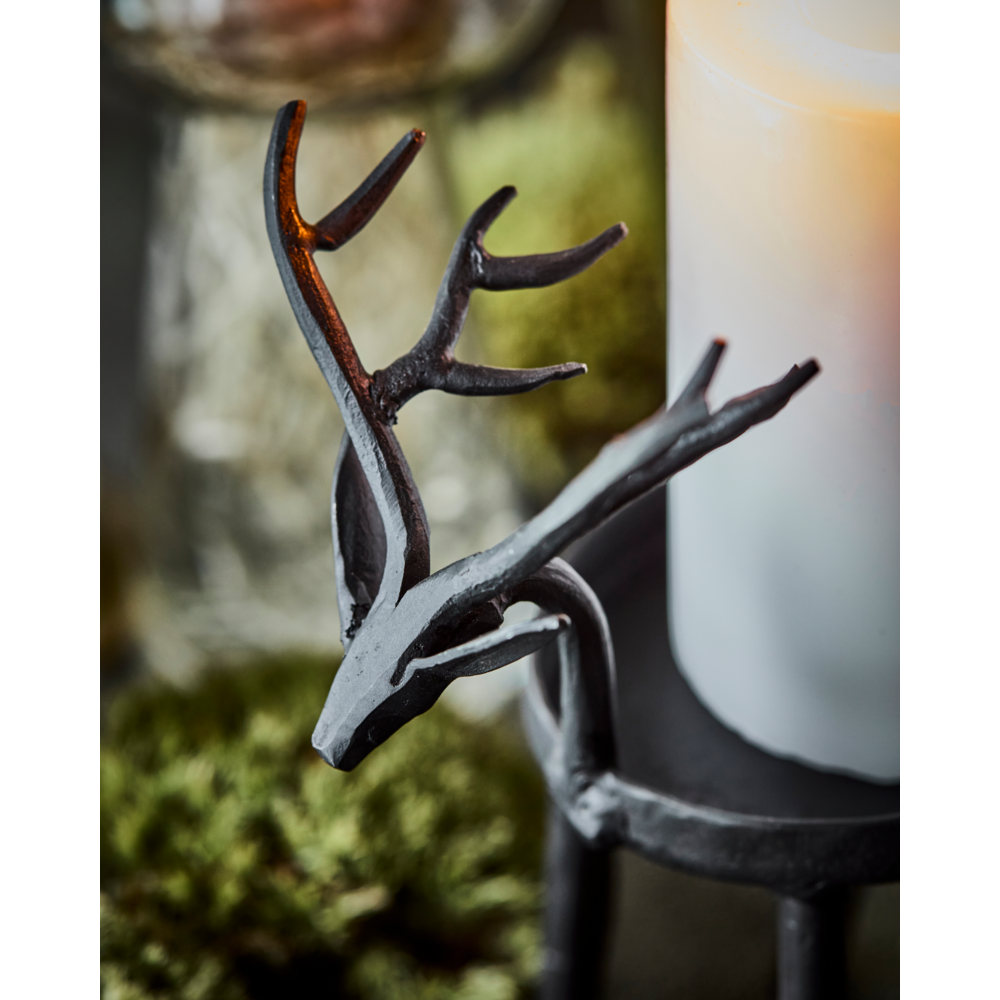 House Doctor Tealight Holder Deer in Iron, Black positioned next to a lit pillar candle.