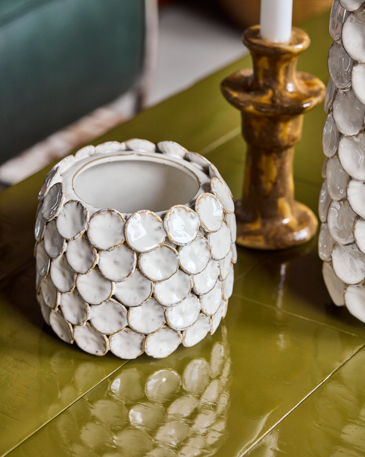 A House Doctor Vase Dot Ceramic 15cm small with circular patterns sits on a glossy green table next to a brown candle holder.