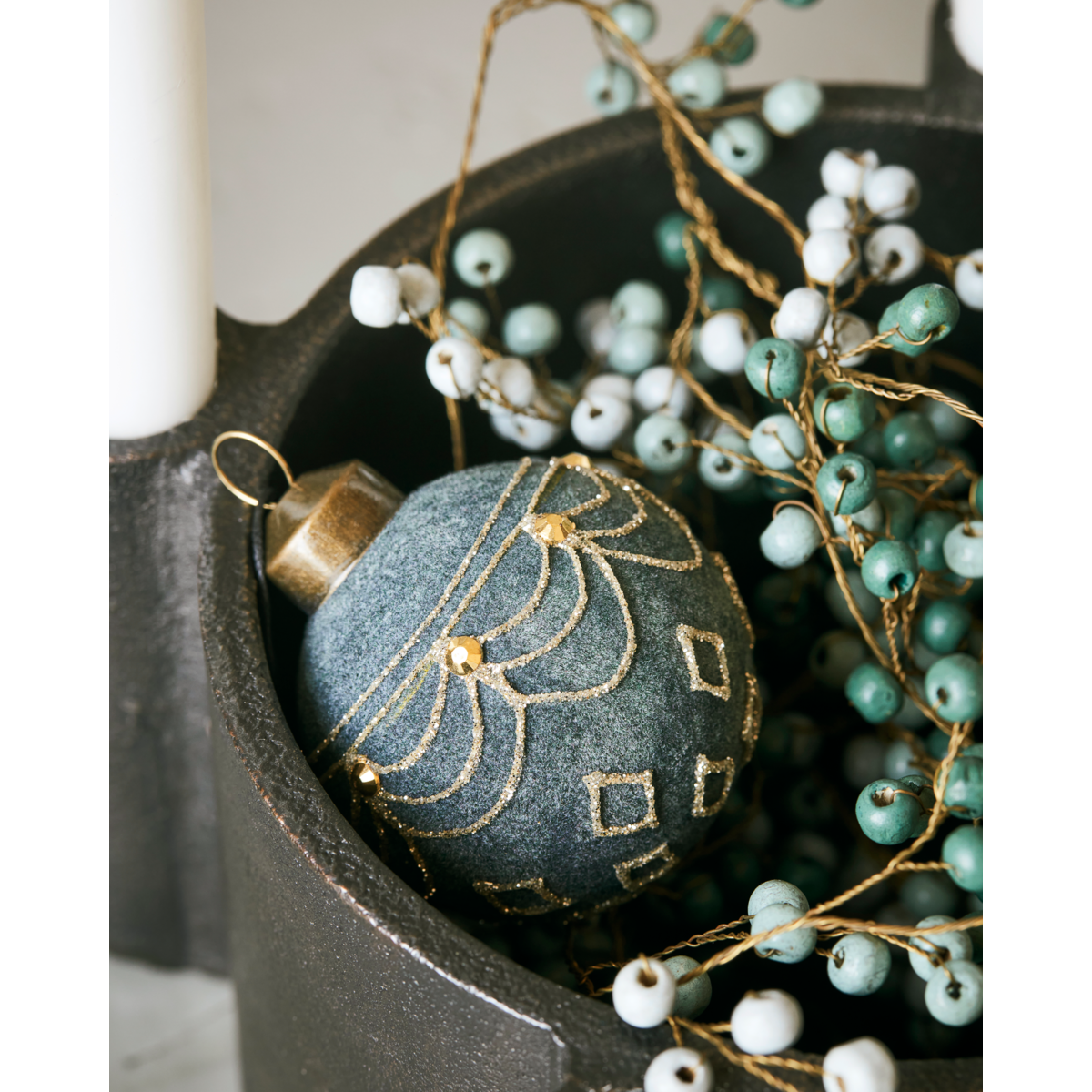 A velour dusty green Christmas ornament bauble by House Doctor is paired with green and white artificial berries in a black container, creating a modern festive arrangement inspired by House Doctor’s holiday decor.