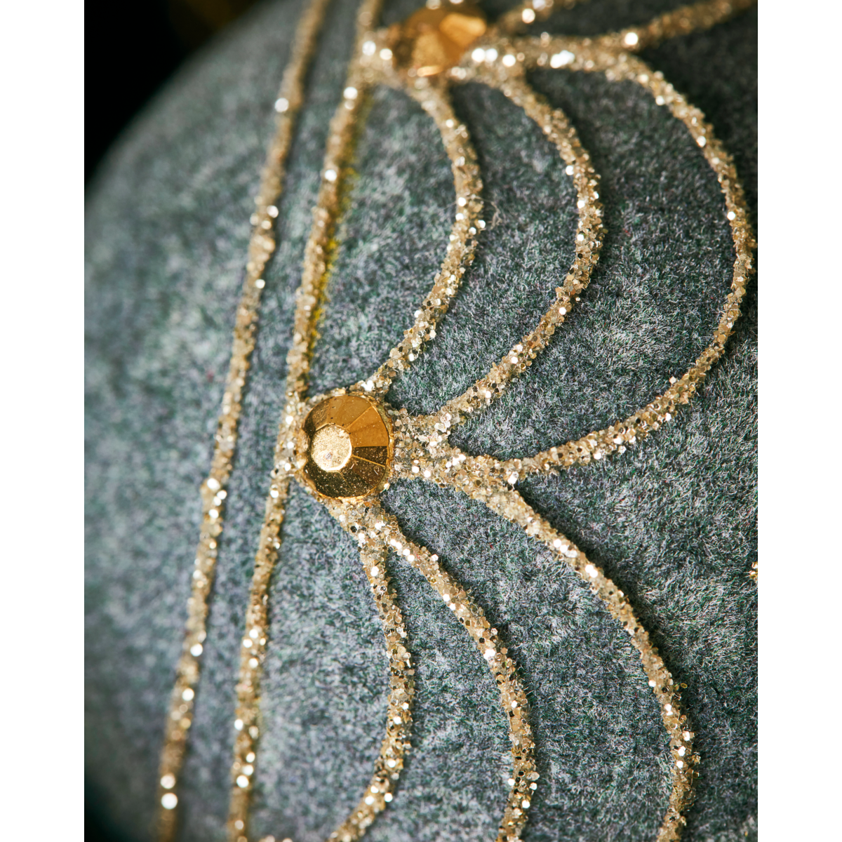 Close-up of a textured gray surface with gold glitter lines and round sequins in a symmetrical, fan-like pattern, inspired by the elegant details on the House Doctor Christmas Ornament Bauble, Velour Dusty Green.