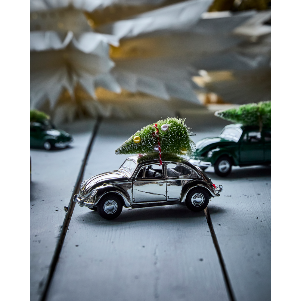 A silver House Doctor Ornament Xmas Car Christmas Decoration with a small decorated tree tied to its roof, sitting on a white wooden surface.