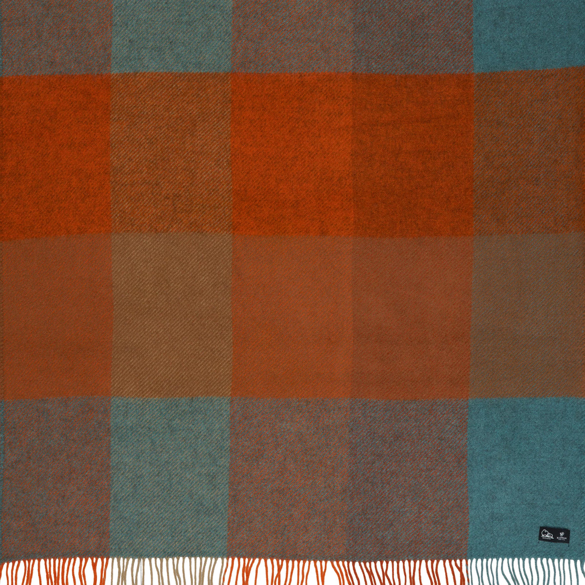 Introducing the Gotland Brushed Gotland & Lambswool Throw in Check Orange by Klippan Yllefabrik—a Swedish wool blanket showcasing a bold checkered pattern in rust orange, teal blue, and brown hues. Finished with striking white and orange fringes along the edge, this cozy lambswool throw brings both warmth and style to any room.