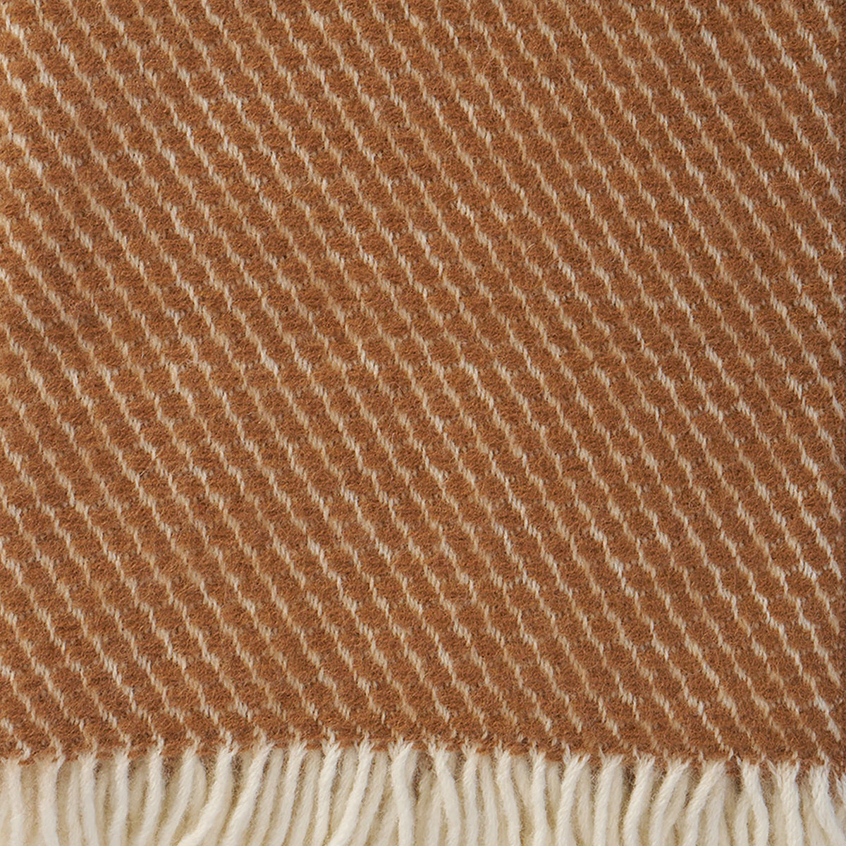 Close-up of the Velvet Mocha Mousse Brushed Lambswool Throw by Klippan Yllefabrik, featuring diagonal stripes in rich mocha and cream tones. The bottom edge is finished with cream-colored fringe, while the soft lambswool texture makes this throw an inviting choice for cozy evenings.