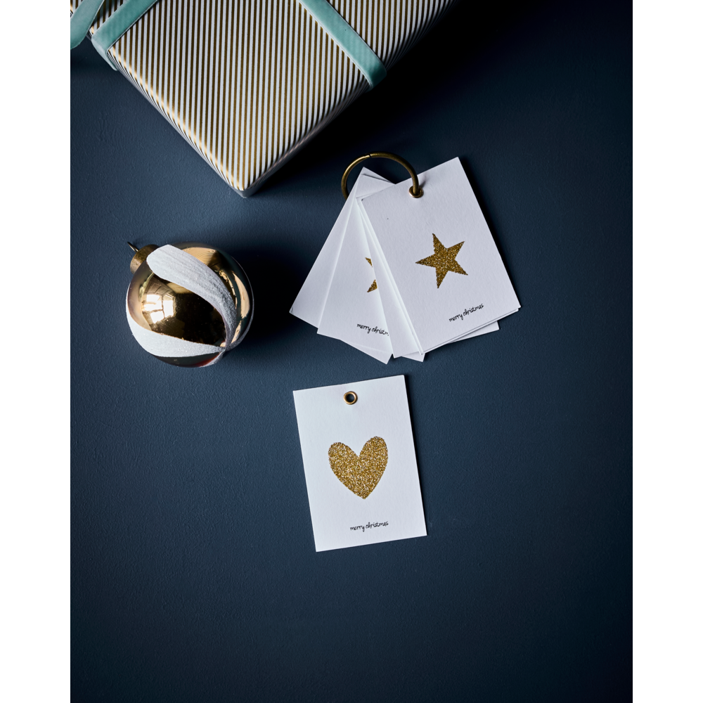 House Doctor Holiday Gift Tags in Gold attached to a metal ring, displayed next to a wrapped gift and a gold ornament.