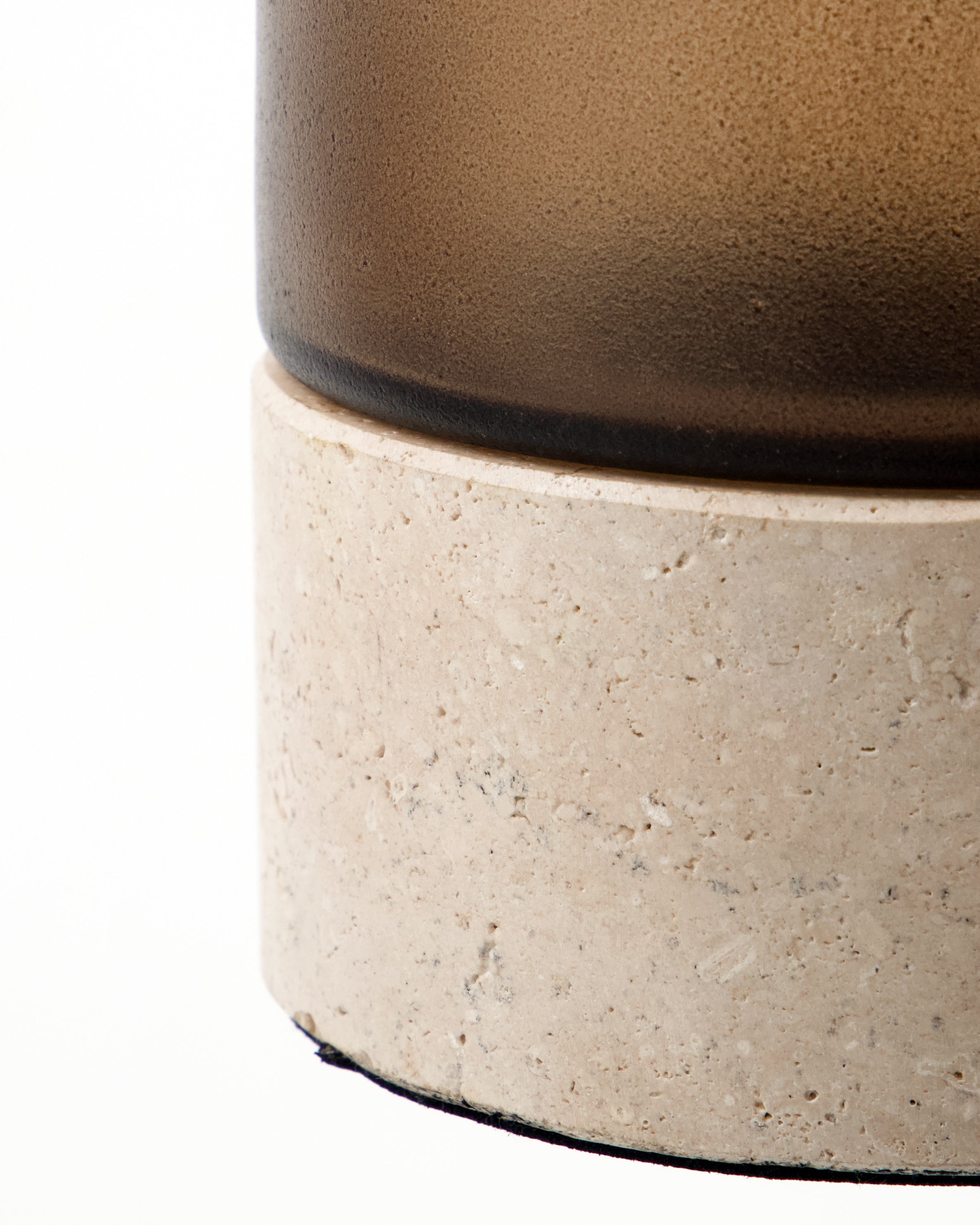 A close-up of the House Doctor Candle Holder Rivo w. Brown Glass, Handmade, featuring a cylindrical design with a frosted brown mouthblown glass upper section and a smooth, light-colored travertine base against a white background.