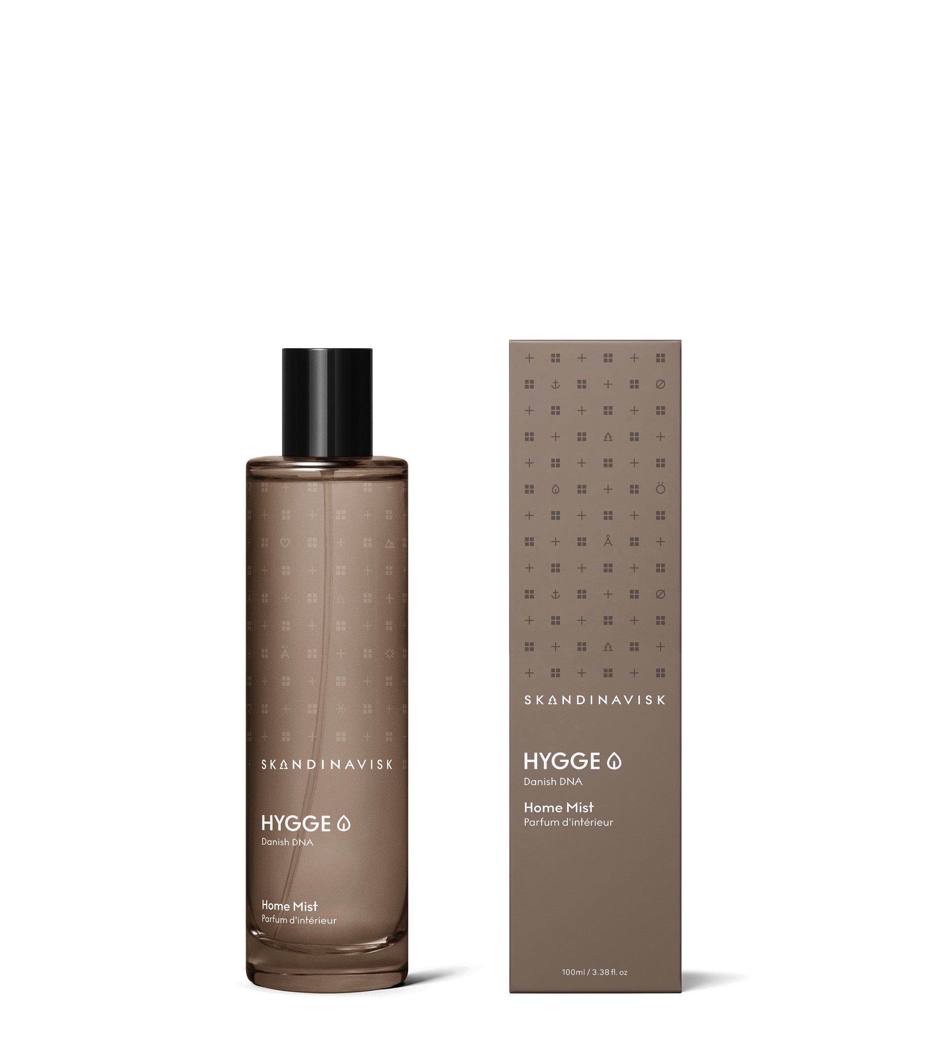 A brown bottle of Skandinavisk Home Mist Hygge, 100 ml, with minimalist labeling inspired by Scandinavian hygge, stands beside its matching brown box adorned with simple text and dotted patterns on a white background, evoking the comforting scent of home.