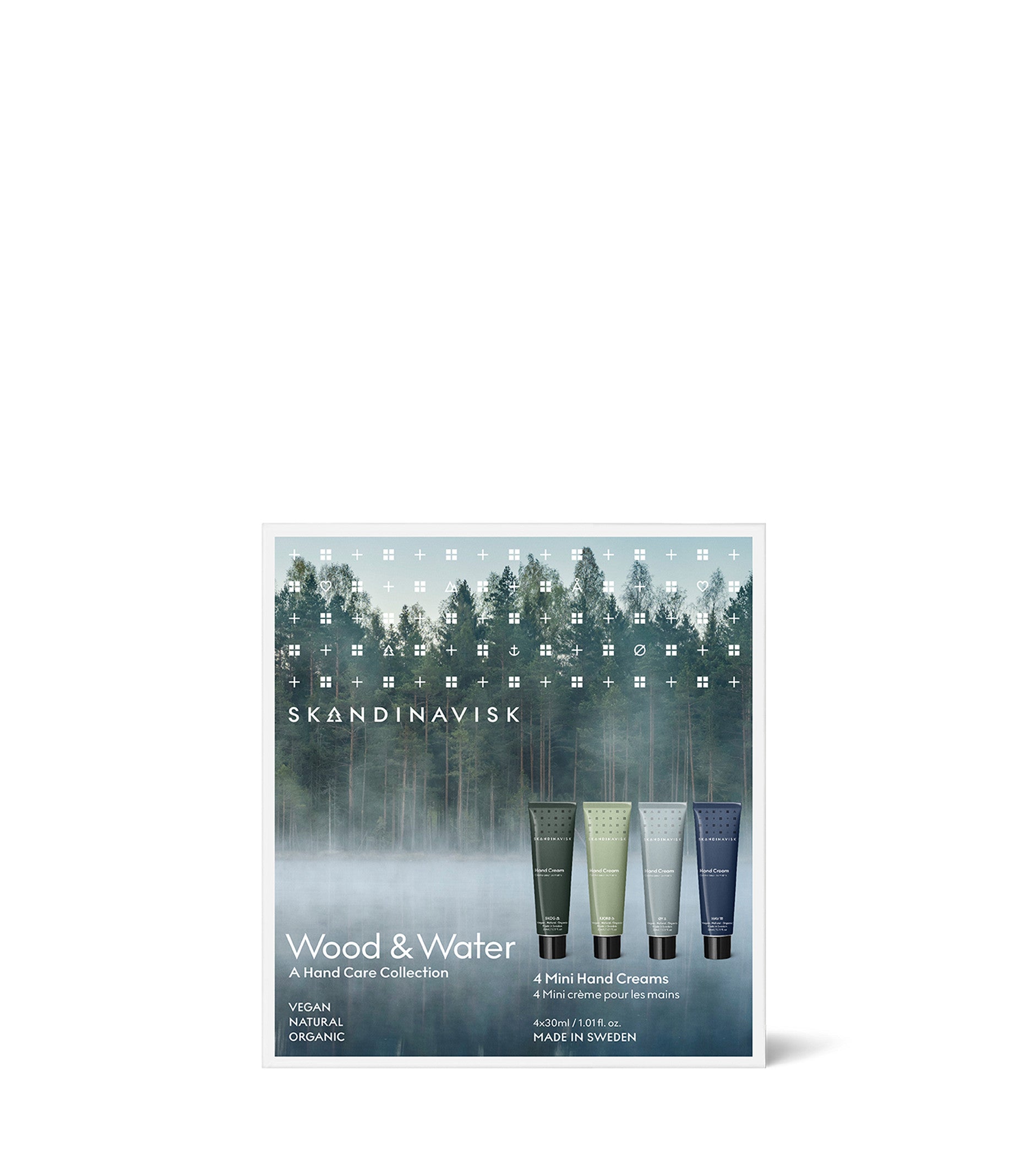 A Skandinavisk Giftset Hand Creams Wood & Water, featuring four mini 30ml hand creams in the scents Skog, Fjord, Oy, and Hav, is displayed against a misty forest background. The packaging emphasizes that the products are vegan, organic, and made with natural ingredients.