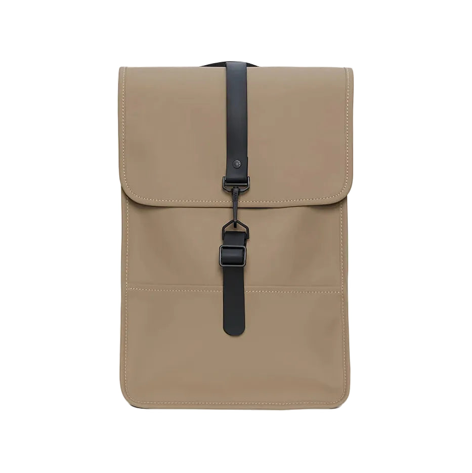 The Rains Backpack Mini Bag in Beige by Rains features a minimalist rectangular design with a flap closure, black strap, and buckle detail. Visible stitching accents its modern silhouette, making it ideal for carrying your essentials as a laptop backpack. Shown against a white background.