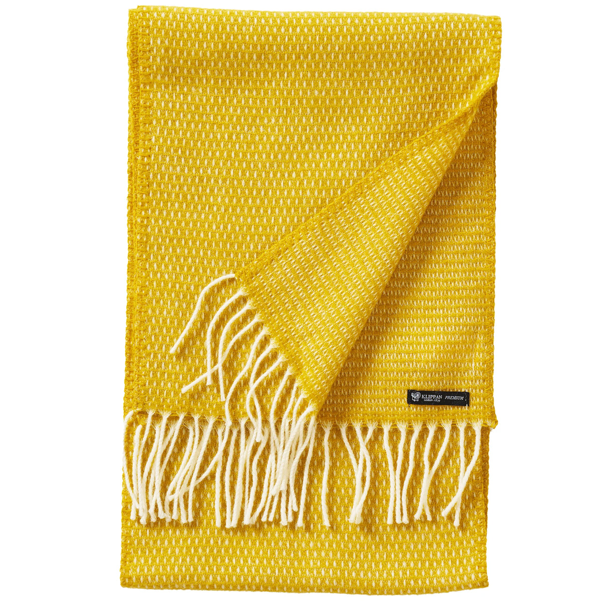 A vibrant saffron yellow scarf by Klippan Yllefabrik, the Hugo Scarf is crafted from a premium blend of recycled and new merino wool. Partially folded to reveal both sides, it features crisp white fringes and a small black label—expertly woven with the same care and finesse as an elegant throw blanket.