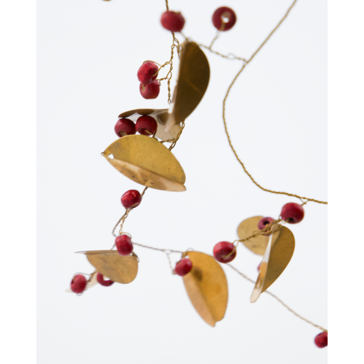 The Garland Leafi in Brass by House Doctor is a 183 cm handmade garland with golden leaves and red bead clusters on gold wire—ideal for elegant Christmas décor.