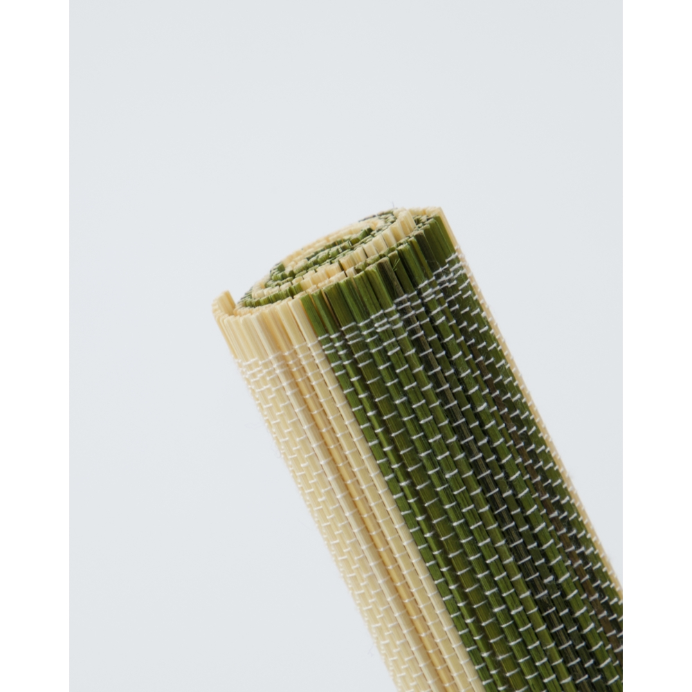 A close-up of a House Doctor "Rayas" placemat from the Green & Nature Stripe set of 4, featuring alternating beige and green bamboo cotton slats, shown rolled on a plain white background.