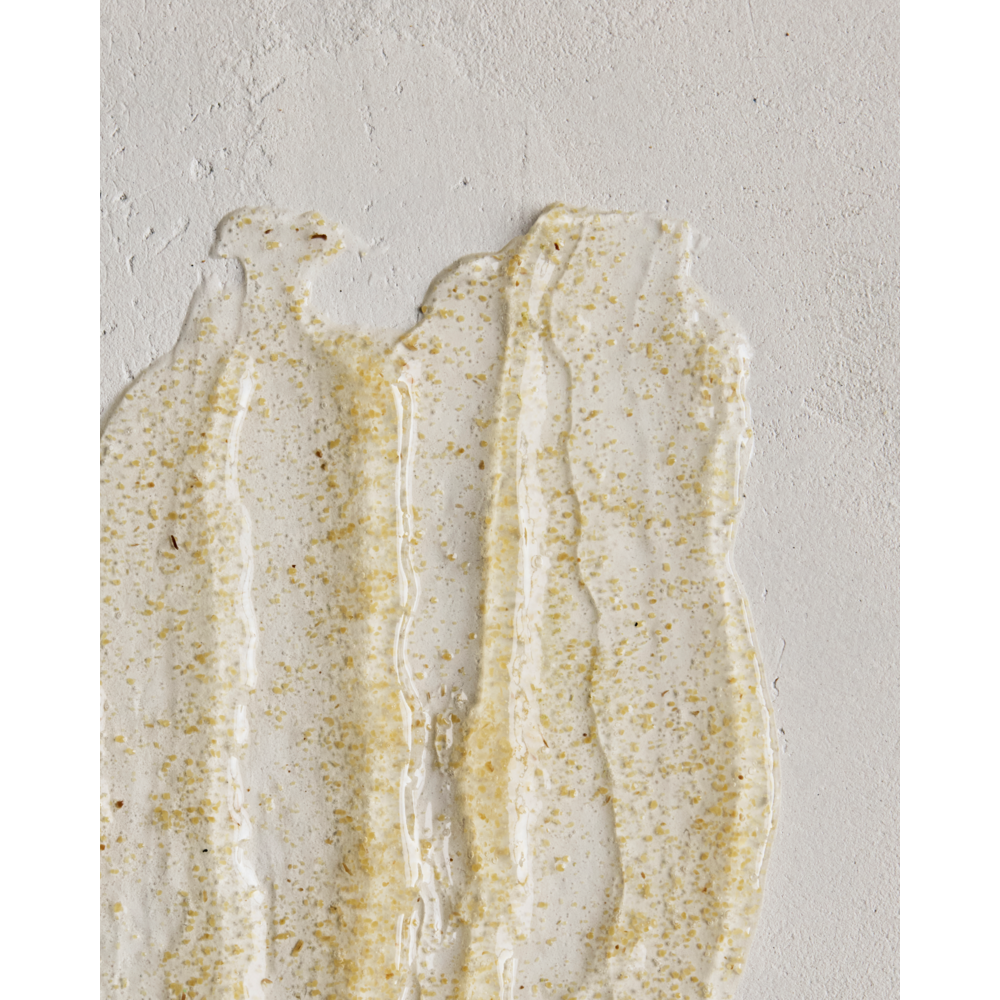 A close-up of Meraki's Body Scrub Organic, Northern Dawn, showing its textured white surface with translucent gel streaks and fine, light brown exfoliating particles spread gently across it.