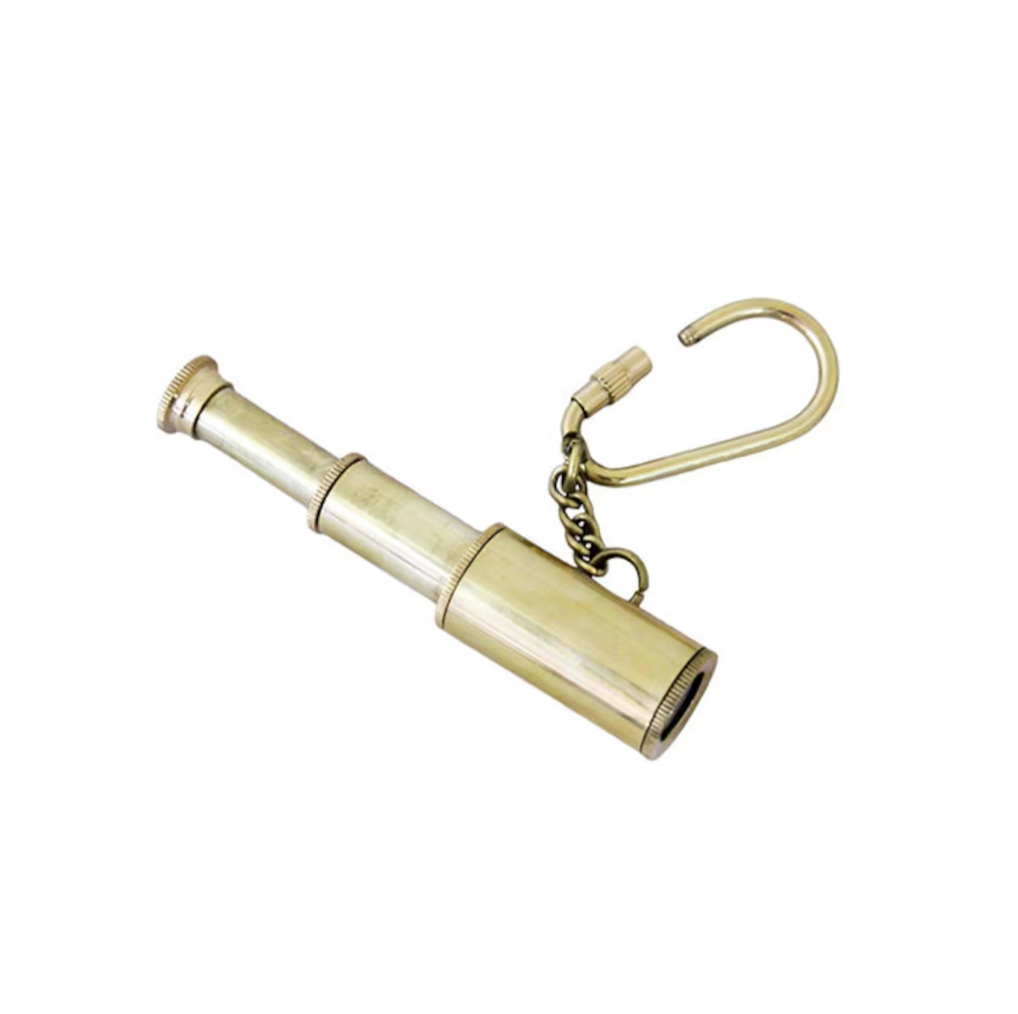 The Strömshaga Key Chain Binoculars Brass features a retractable lens and a large curved brass key ring on a short chain—an ideal accessory for adventurers, shown against a white background.