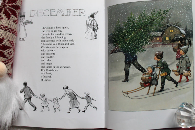 The Around the Year Mini Edition Book by Elsa Beskow features a December-themed Christmas poem on the left page and, on the right, an illustration of children and adults carrying a Christmas tree in snowy scenery.