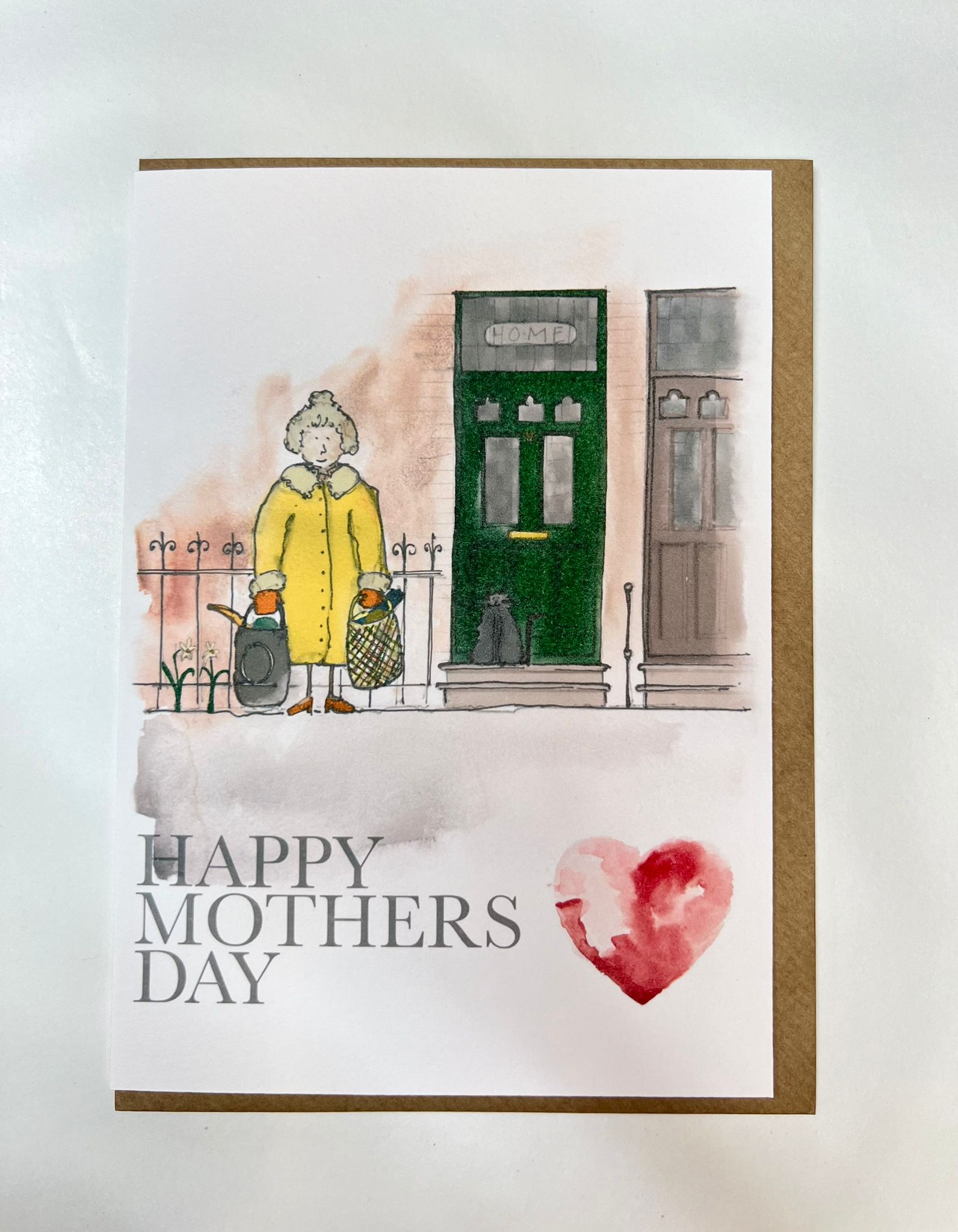 Blåbär Nordic Living's "Mothers Day Card - Shopping Mum" features a Nordic design with an older woman in a yellow coat by a green door. Bold “HAPPY MOTHERS DAY” and a red watercolor heart make this the perfect handcrafted card.