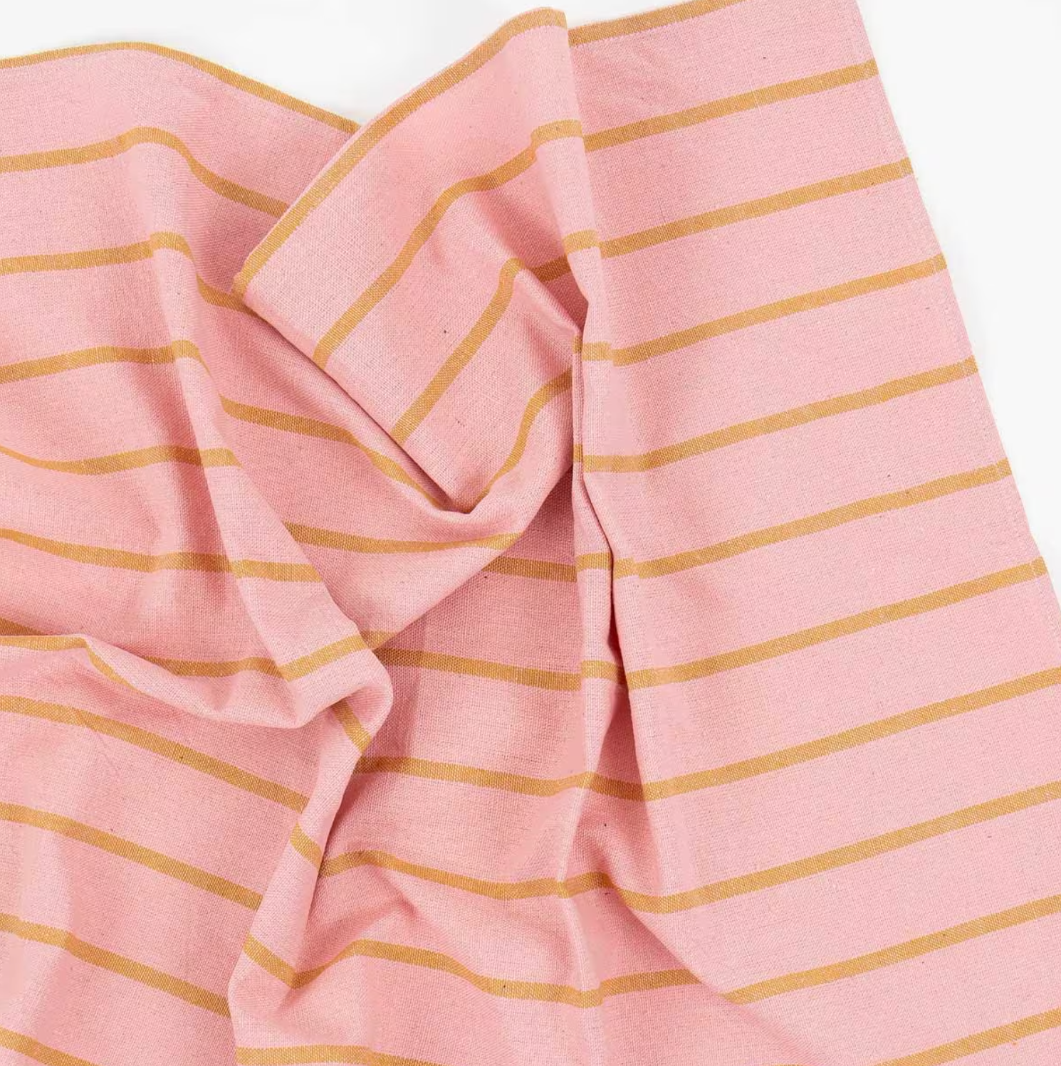 A World of Craft’s Tea Towel, Wide Stripe Pink & Mustard in organic cotton, is handwoven and features pink fabric with wide mustard-yellow horizontal stripes, loosely draped to create soft folds and gentle wrinkles.