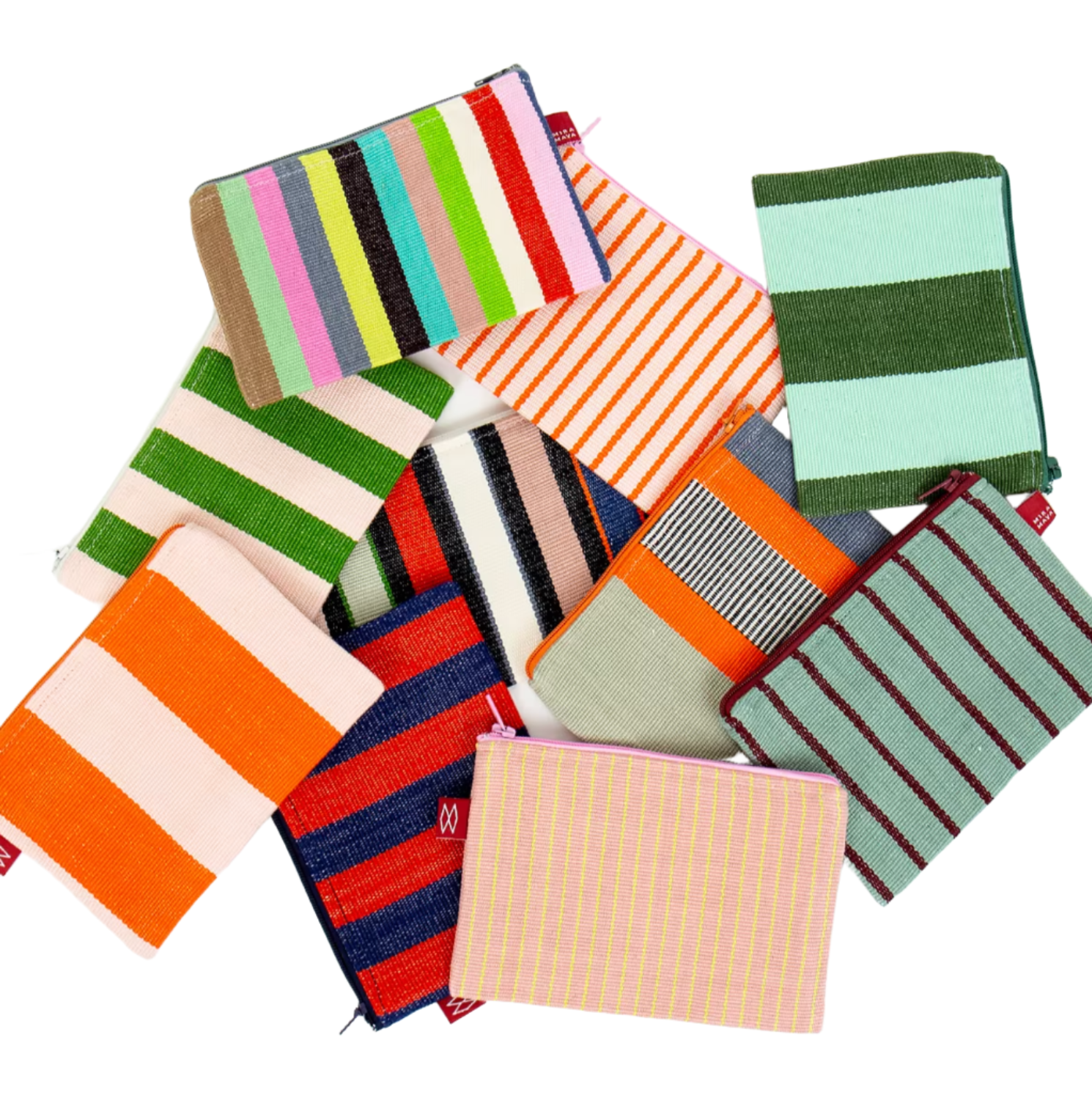 A scattered pile of Mira Maya Purses by A World of Craft—small, handmade fair trade pouches with colorful striped patterns inspired by traditional weaving—displayed on a white background.