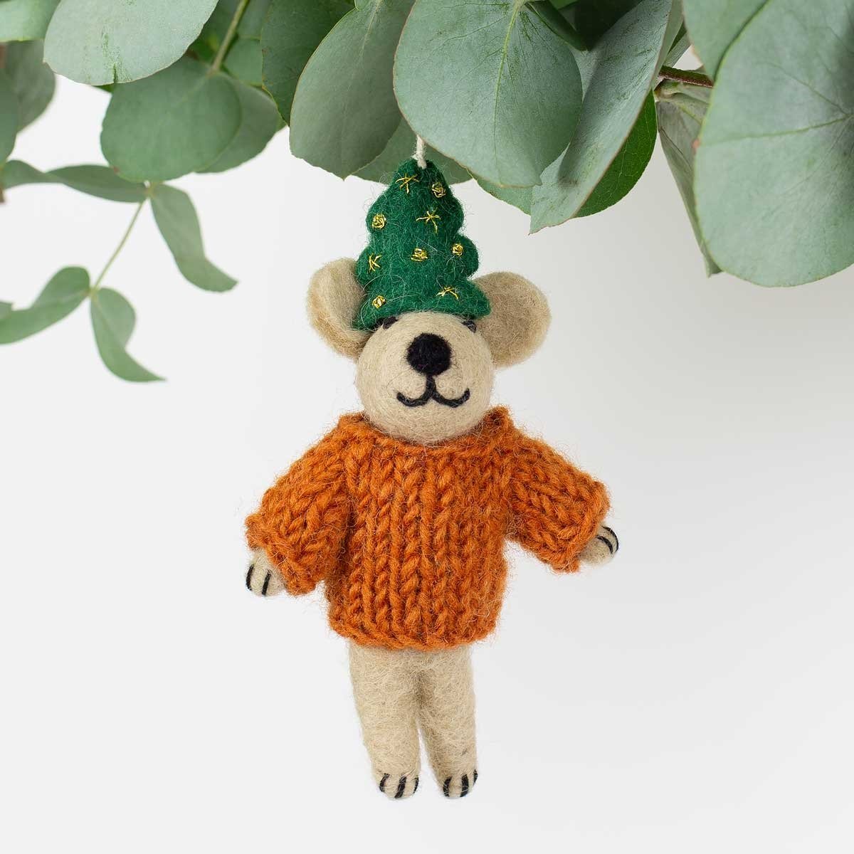 The Bear w. Christmas Tree hat, a 13 cm handmade wool ornament from A World of Craft, features an orange sweater and green tree hat—perfect as a Fairtrade accent for your festive décor.