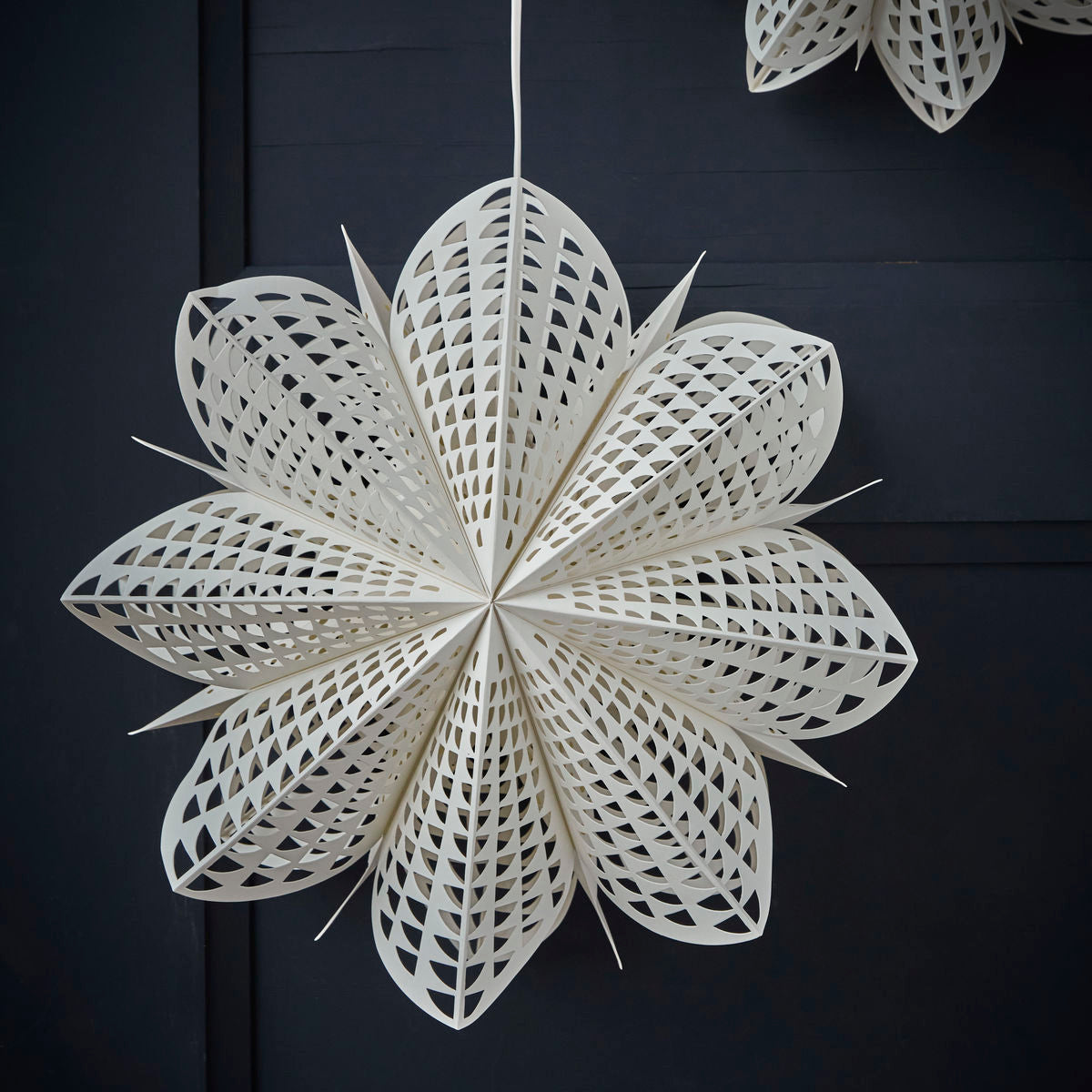 The Gint Paper Star, 45 cm by House Doctor, features intricate cuts and serves as a stunning Christmas decoration when displayed against a dark background.