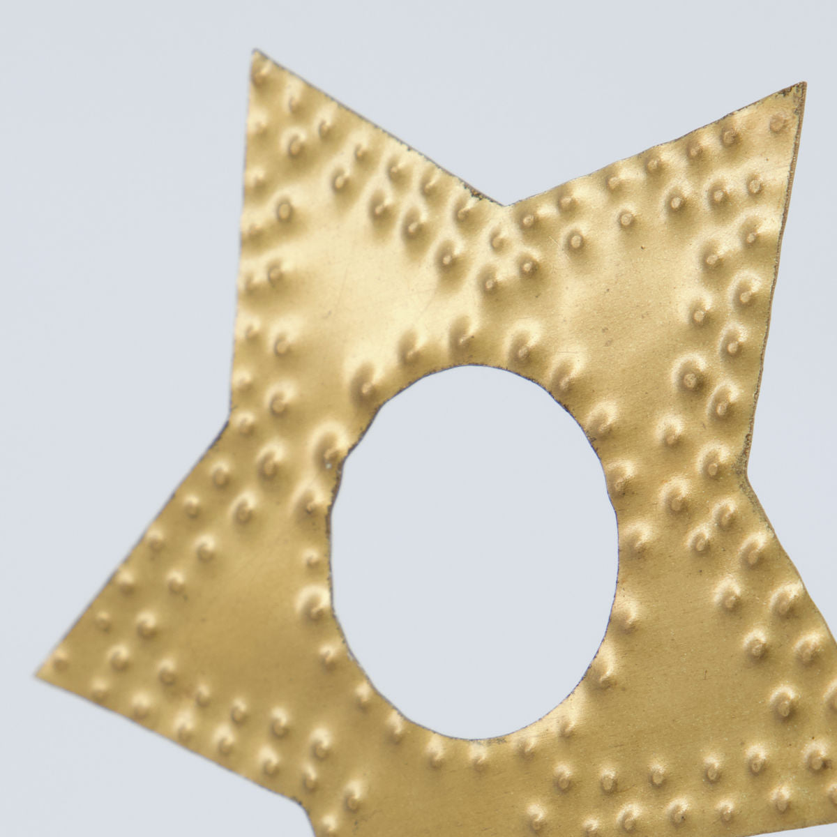 Close-up of a House Doctor Candle Rings Star in Brass, featuring a star shape with a central circular hole, reminiscent of golden candle holders. Sold as a set of 3.