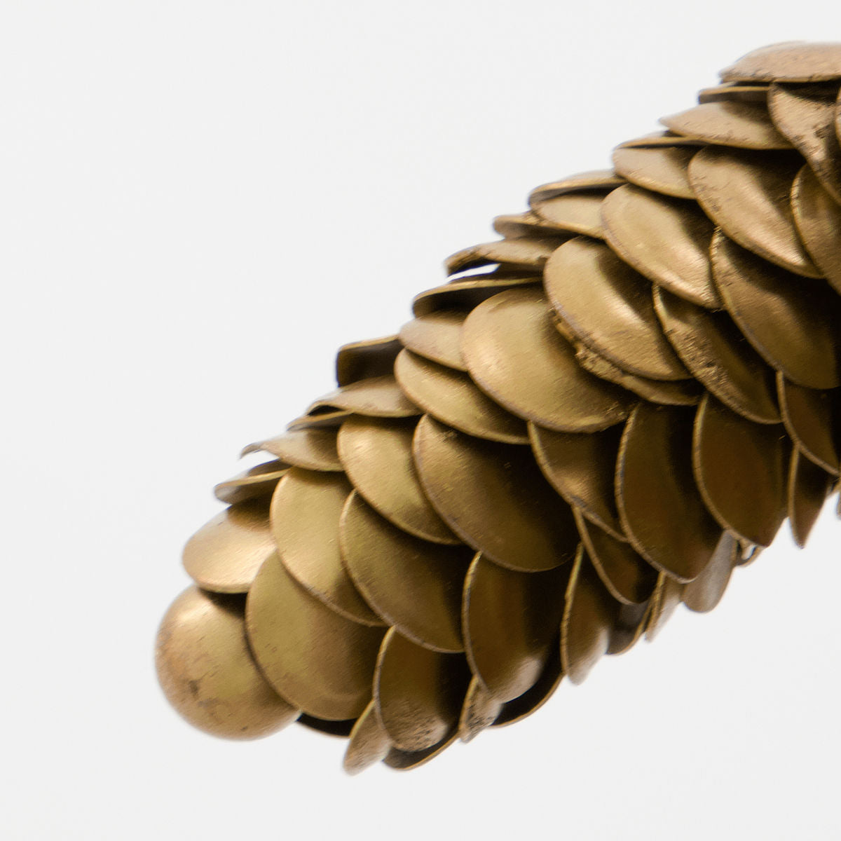 Close-up of House Doctor’s Ornaments Pinecones in Iron, Set of 2—gold, cone-shaped pieces with overlapping metal scales—elegant Christmas décor against a white background.
