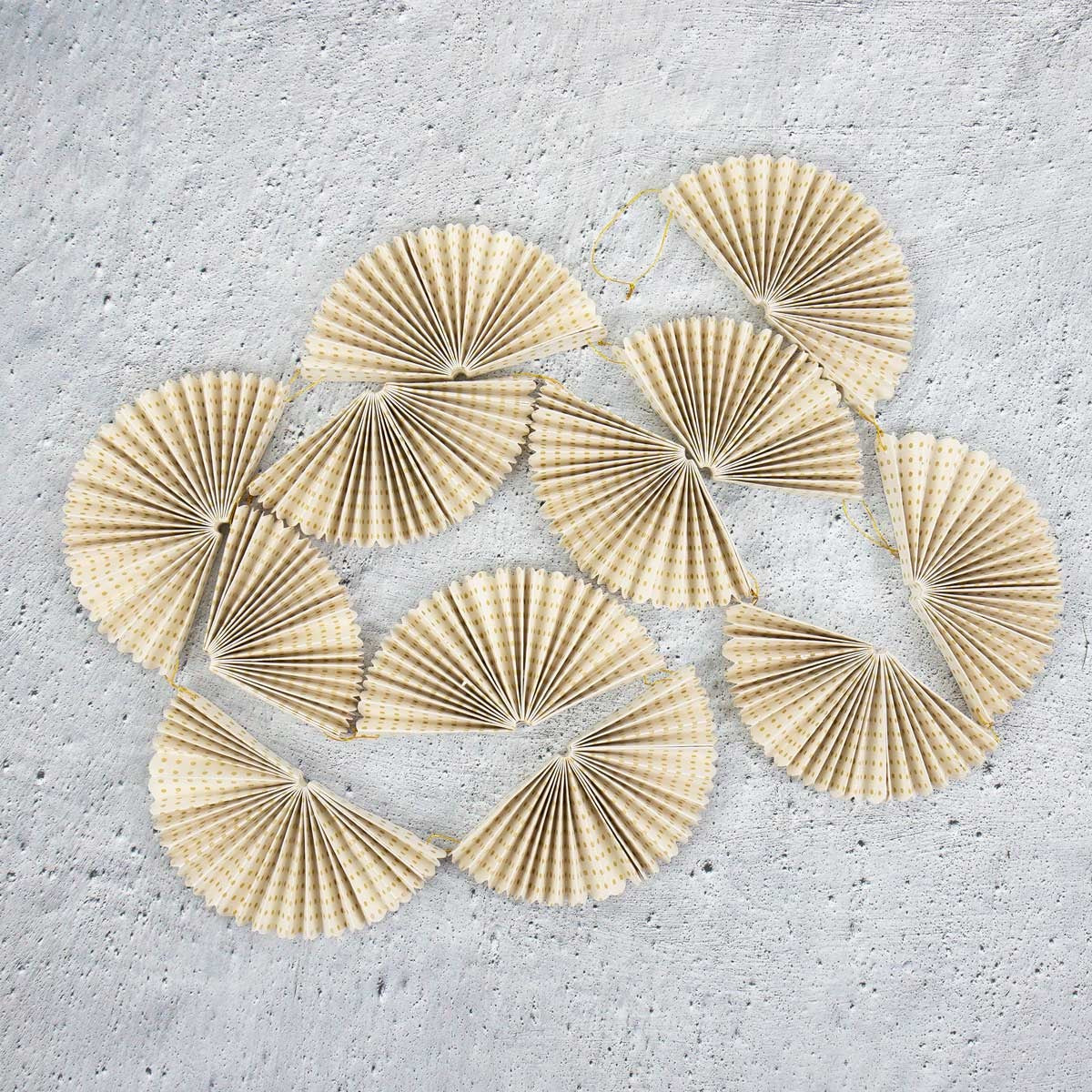 Greta Fold Garland in Gold & White featuring several paper fans strung together as festive holiday decor.
