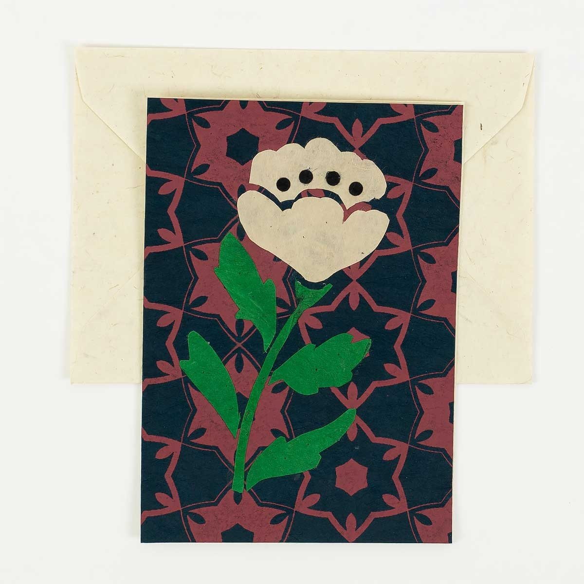 The Poppy Handmade Greeting Card by A World of Craft features a stylized white flower on a maroon and black geometric background, paired with a beige envelope—all crafted from elegant handmade Lokta paper.