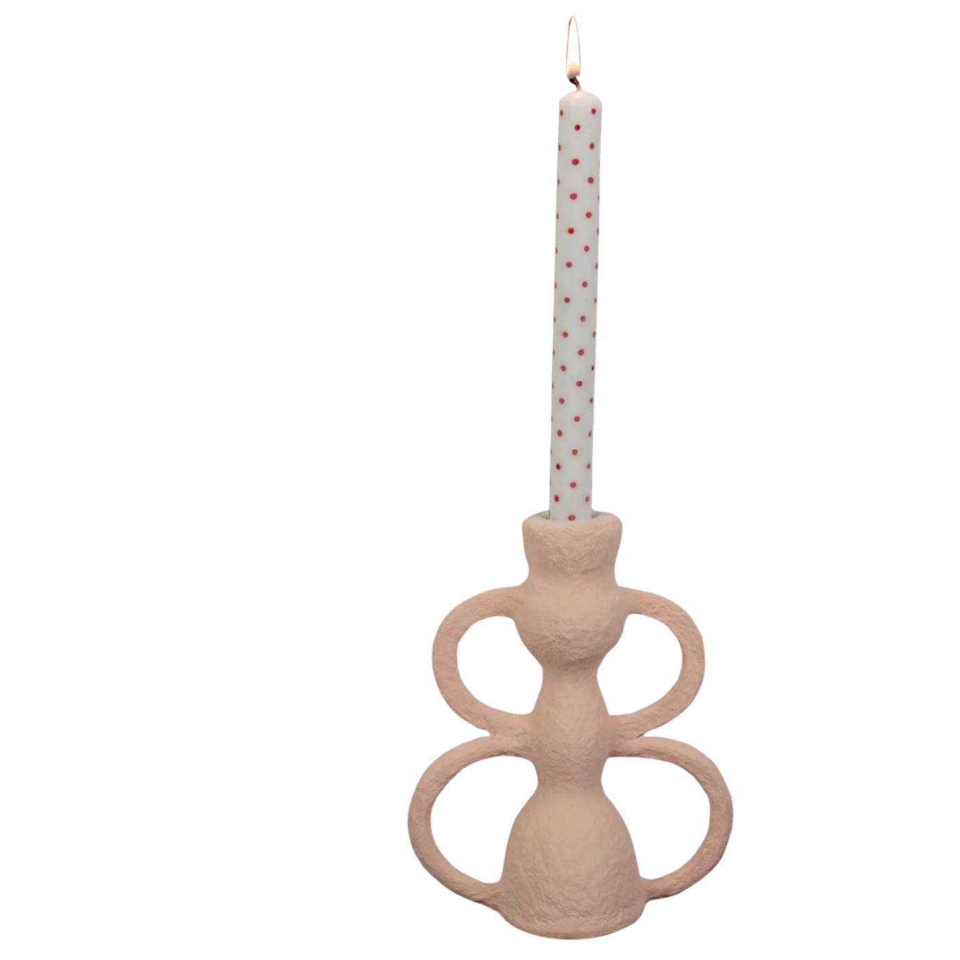 A white candle with red polka dots burns in A World of Craft’s Candle Holder Papier, handmade in pink papier-mache, featuring sculptural looping handles, set against a plain white background.