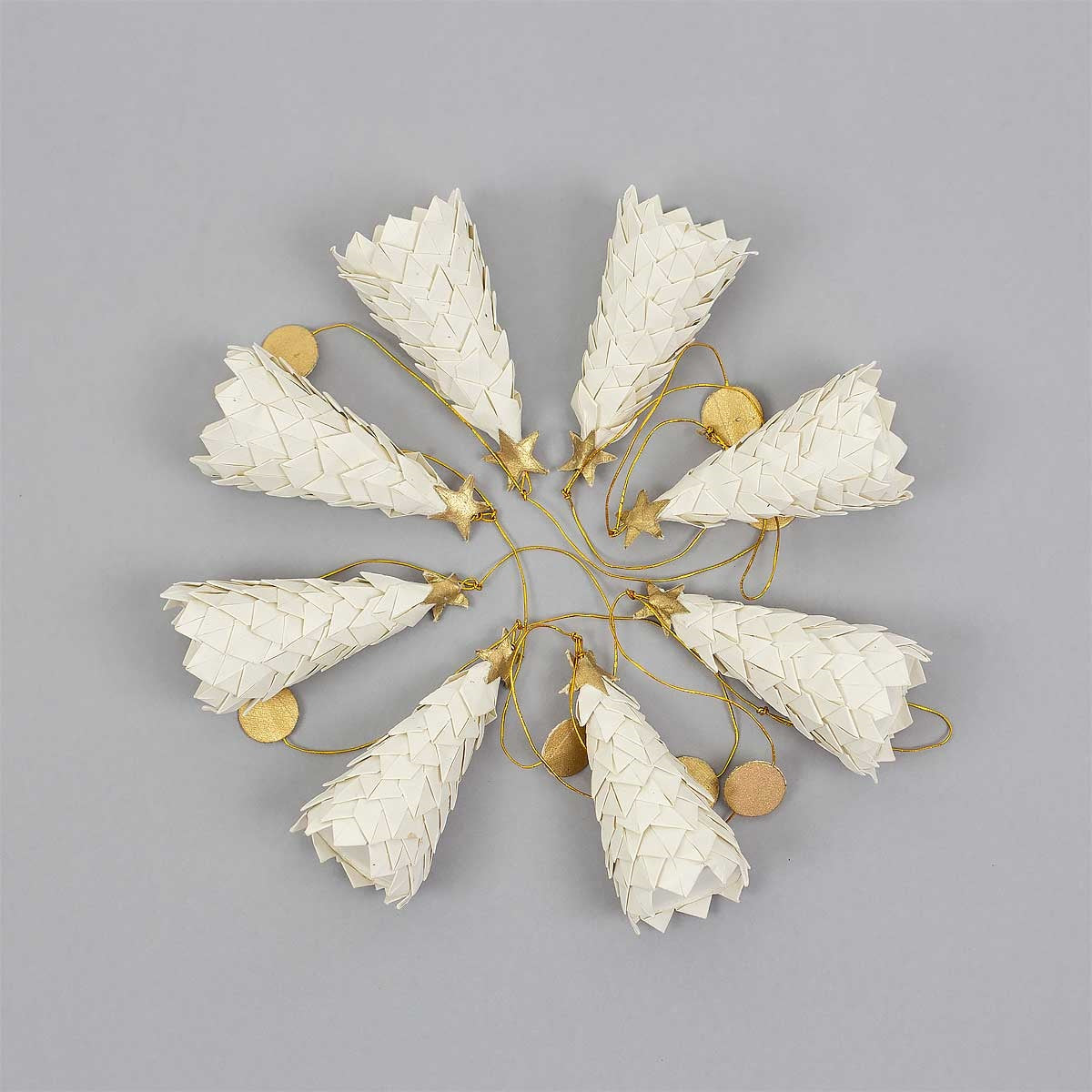 Nine white, cone-shaped ornaments handmade to resemble fir trees are arranged in a circle on a gray background, each adorned with gold string, stars, and round gold tags—perfect for creating an elegant and eco-friendly holiday display with the White Fir Garland from A World of Craft.
