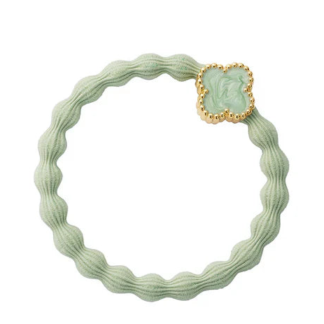 A pistachio green Bangle Band Enamel from ByEloise, featuring a wavy elastic design adorned with a gold-edged quatrefoil charm in mint enamel and delicately woven with silk thread for added elegance.