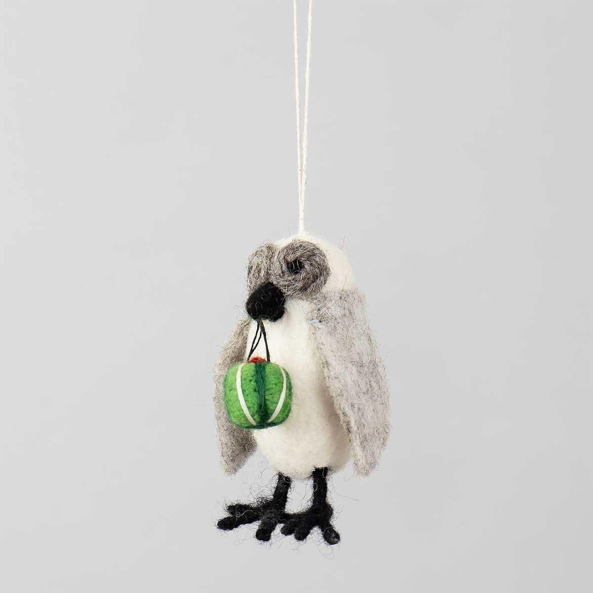 The Wool Owl w. Present Christmas ornament by A World of Craft is an 8 cm handmade wool owl with gray wings, holding a small green present and hanging by a string against a plain light background.
