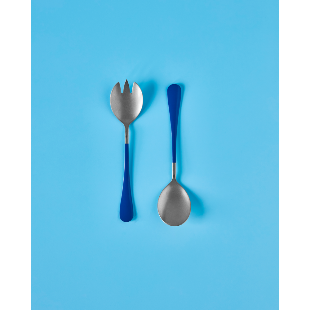 The Nicolas Vahé Salad Set in Stainless Steel, Blue features two utensils with blue handles—a spork and a spoon—shown side by side on a bright blue background.