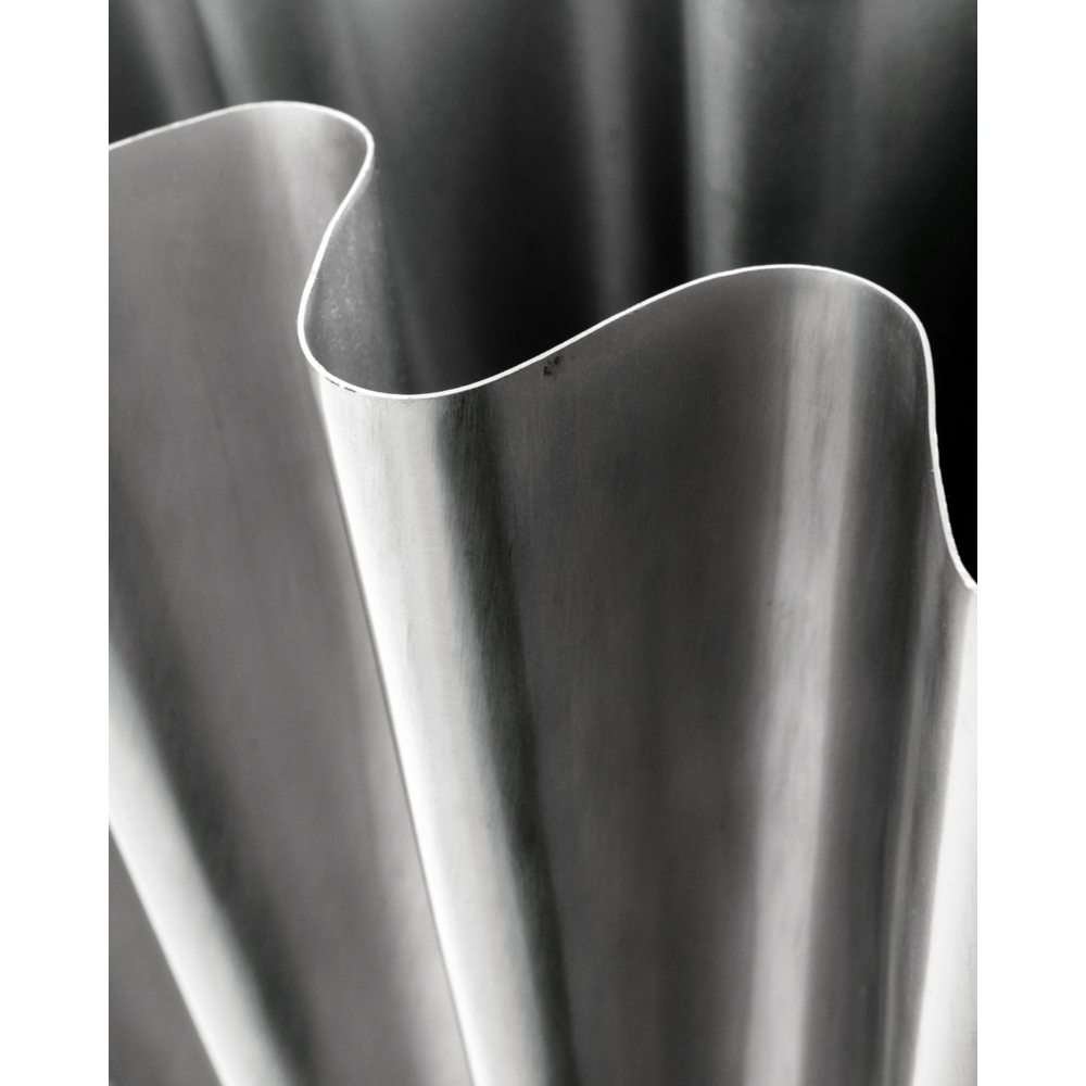 Close-up of the Vase, Flood by House Doctor, featuring a wavy, sculptural form with smooth curves and a matte brushed silver finish. The abstract design highlights its textured folds, evoking the look of brushed silver.