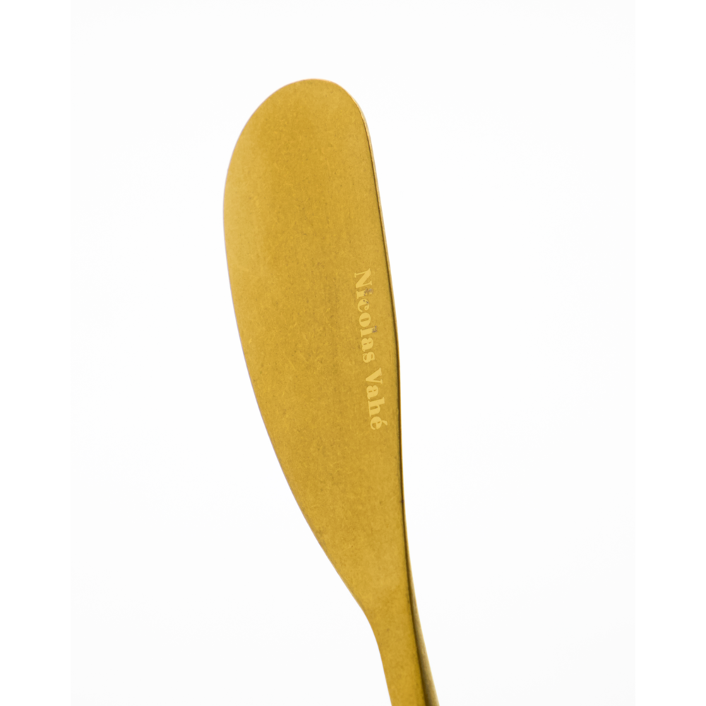 A set of 4 butter knives in an antique gold finish by Nicolas Vahé, each engraved with the brand name and shown on a plain white background.