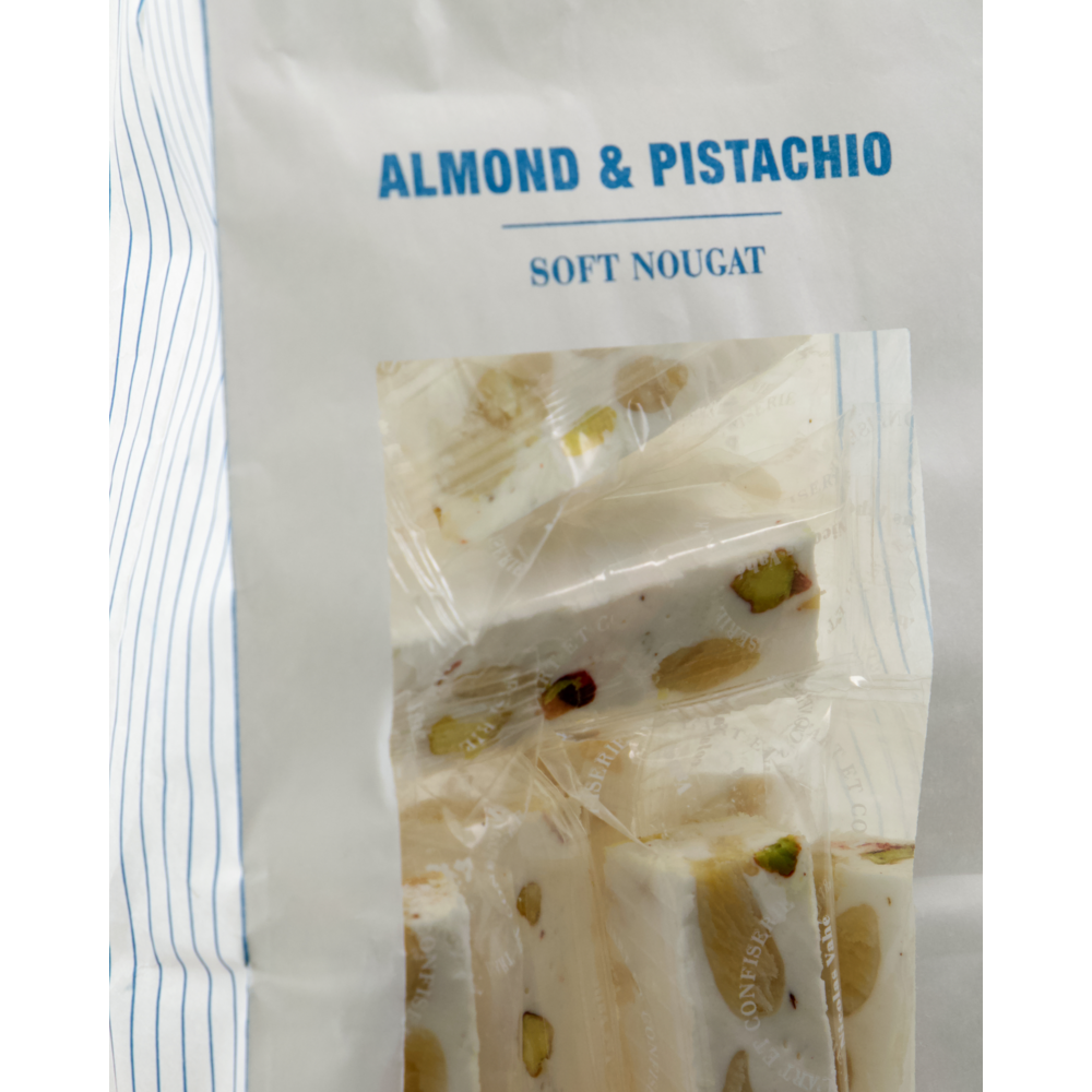 A close-up of a package labeled Nicolas Vahé Soft Nougat, Almonds & Pistachios 150g, featuring individually wrapped nougat pieces with visible almonds and pistachios, proudly made in Italy.