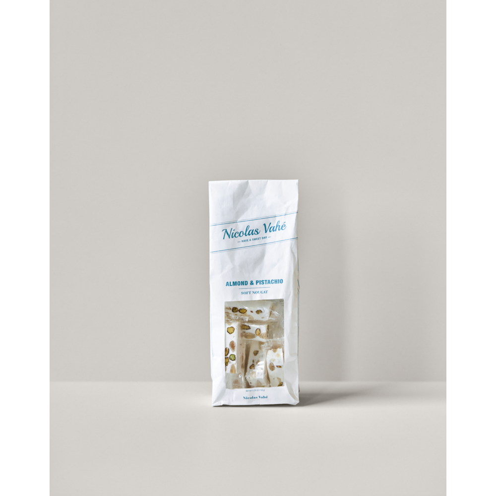 A white bag of Soft Nougat, Almonds & Pistachios 150g from Nicolas Vahé stands upright on a light surface with a neutral background. The nougat features crunchy almonds and pistachios.