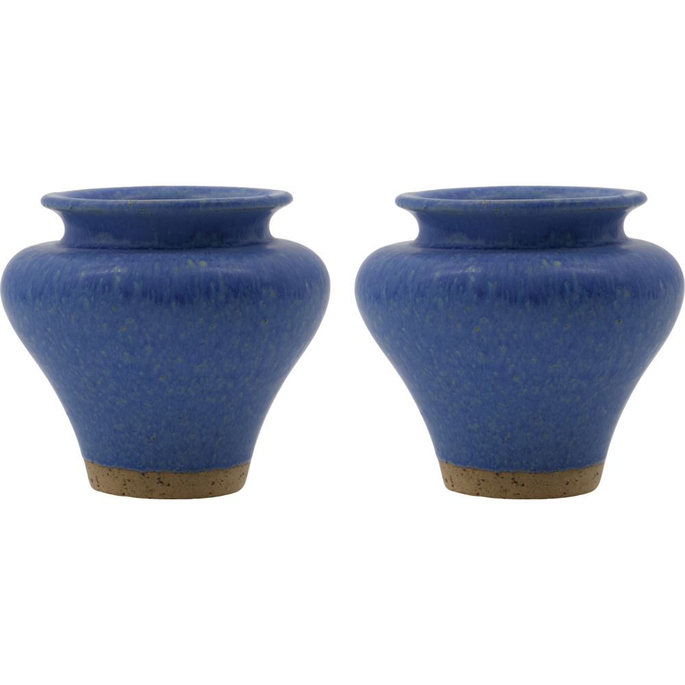 The House Doctor Kolo Blue Vase Set of 2 features round ceramic vases with wide mouths, narrow bases, a speckled blue glaze, and unglazed brown bottoms, displayed side by side on a white background.